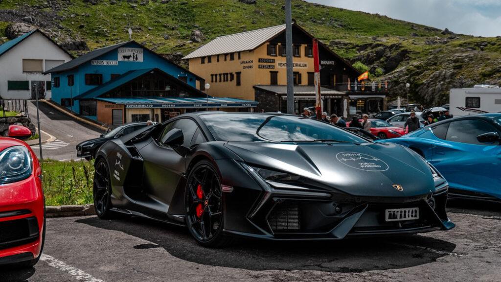 Schwarzer Sportwagen vor Berghütte in malerischer Alpenlandschaft abgestellt.