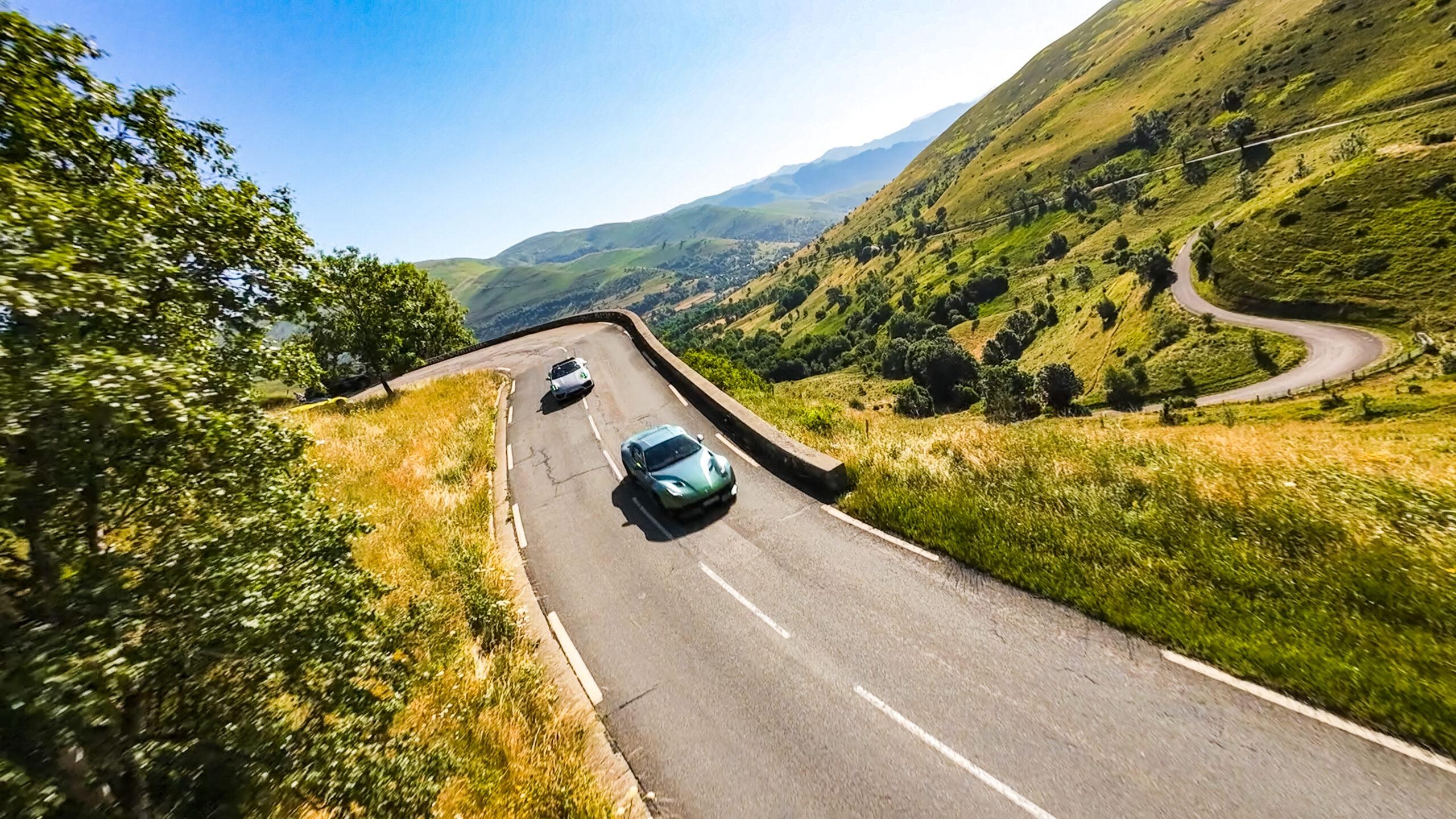 Sportwagen fahren auf einer malerischen Bergstraße in den grünen Alpen.