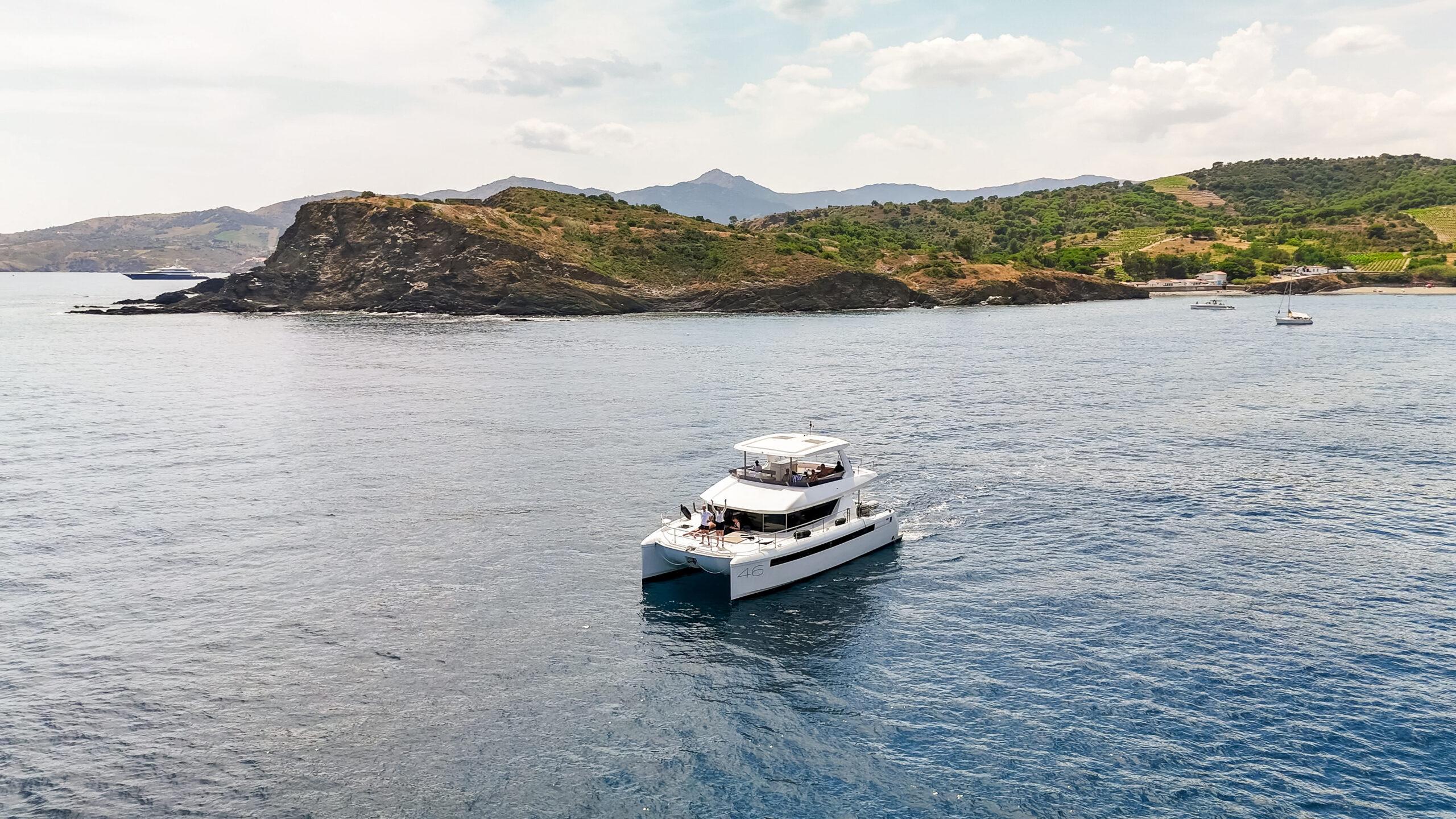 Eine luxuriöse Yacht segelt entlang der malerischen Küste bei sonnigem Wetter.