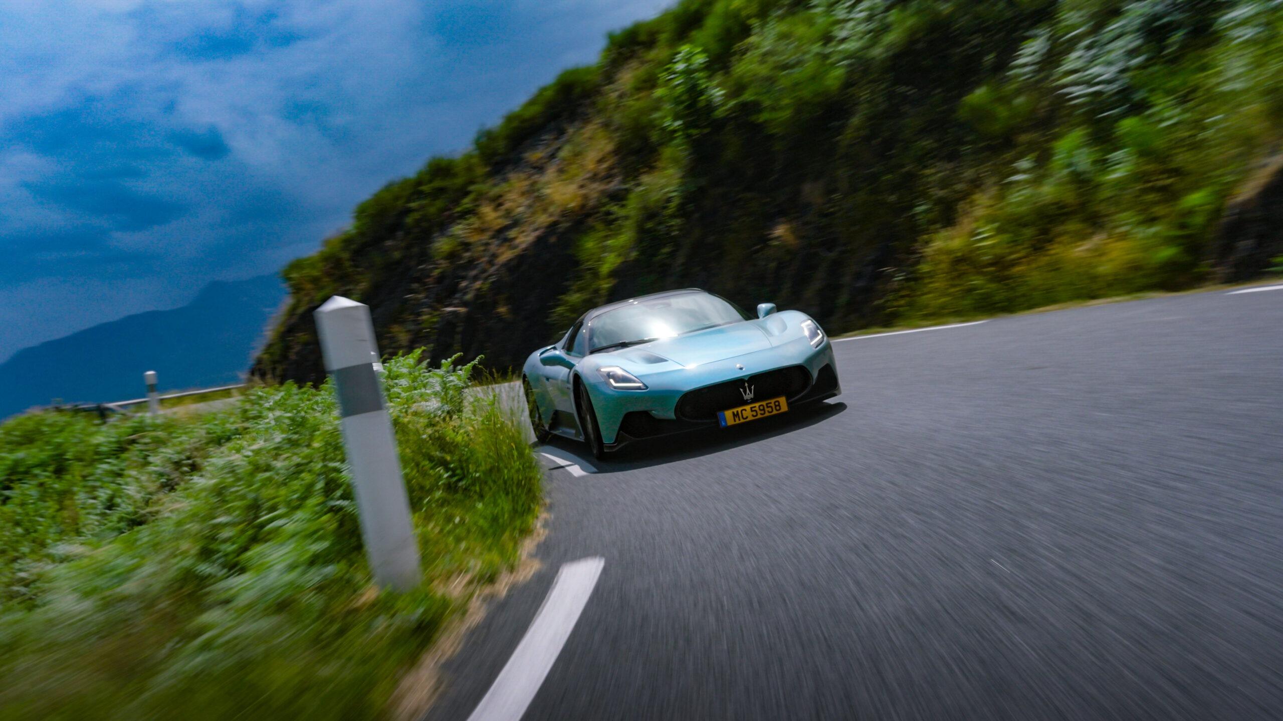 Luxus-Sportwagen auf kurvenreicher Bergstraße in den Alpen bei dramatischem Himmel.