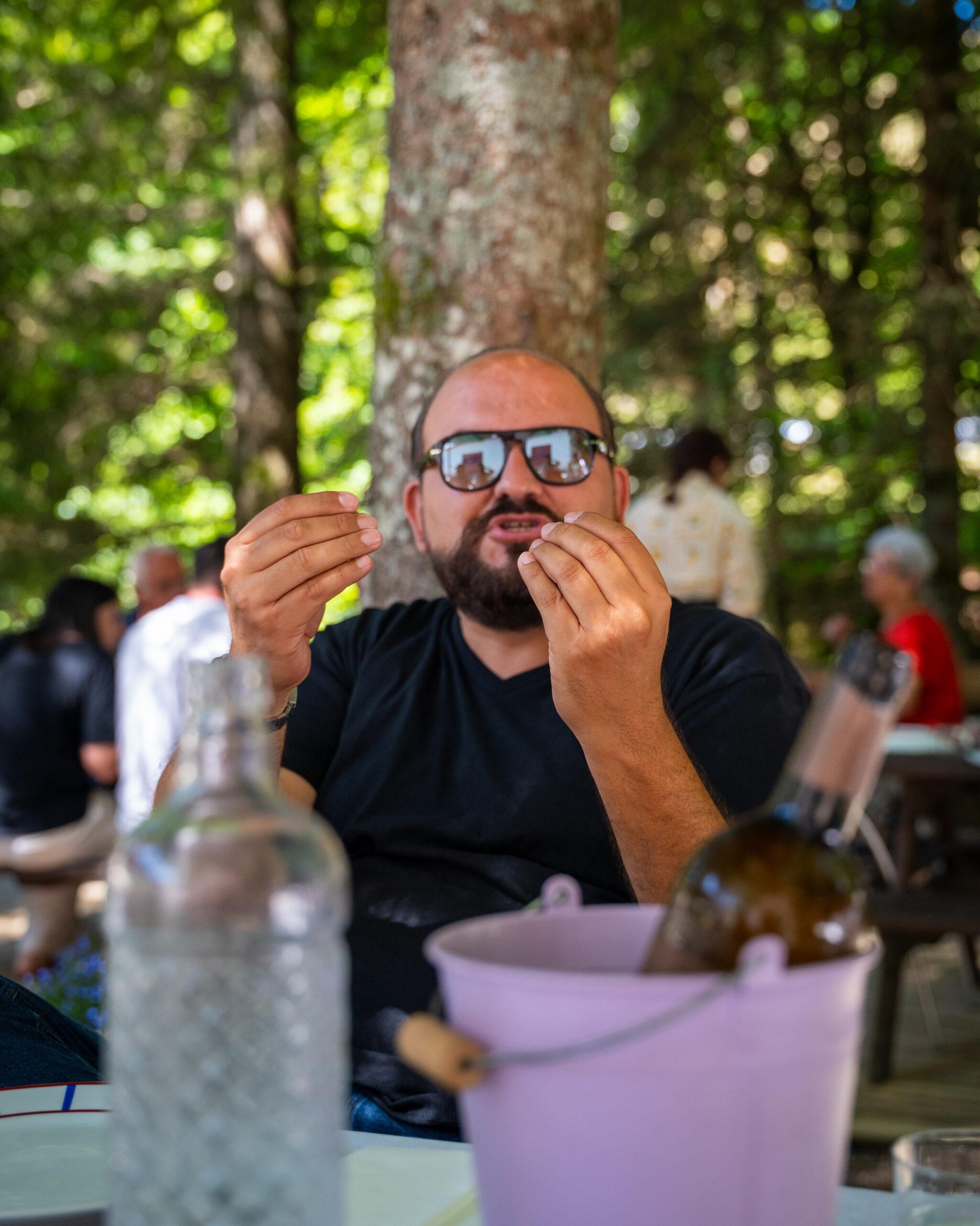Teilnehmer genießt gestenreich ein Mittagessen im Freien während der Vuelto-Pyreneo-Tour.