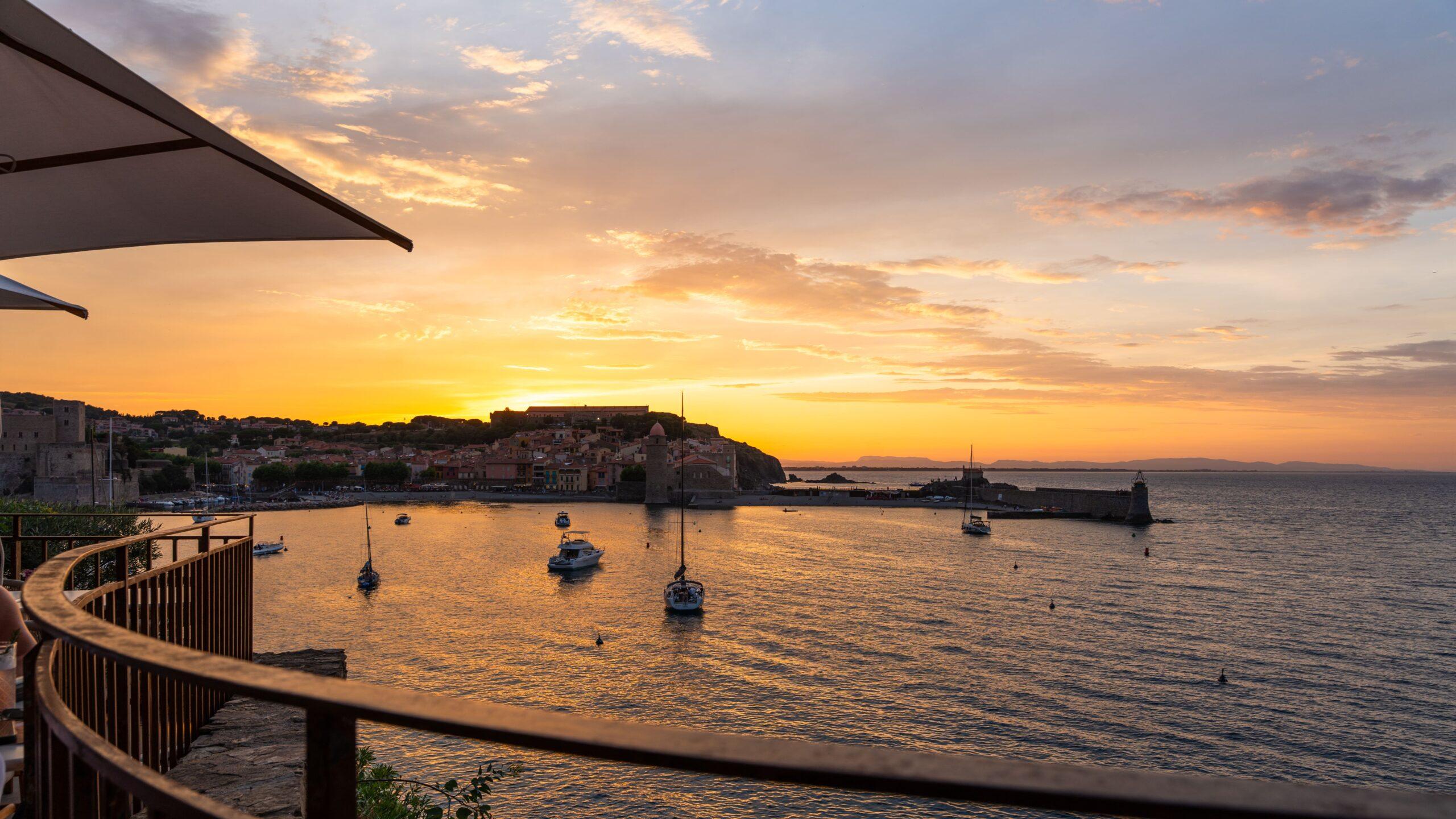 Sportwagen Erlebnisreisen: Malerischer Sonnenuntergang über der Küstenstadt und dem Hafen.