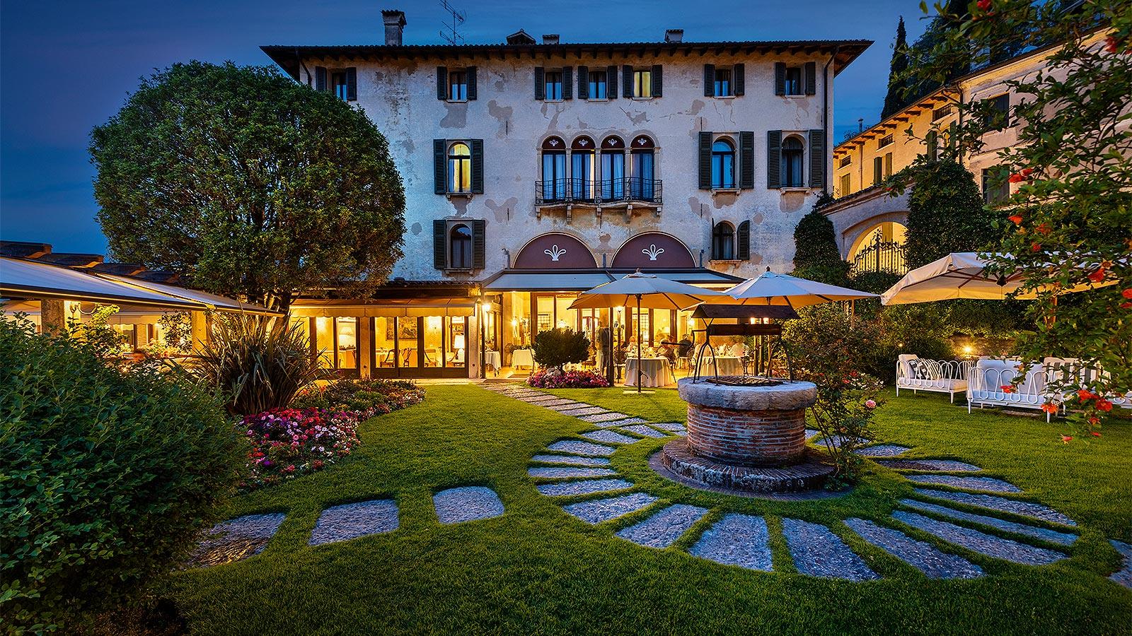 Luxuriöses Hotel mit beleuchtetem Garten bei Abenddämmerung in den Dolomiten.