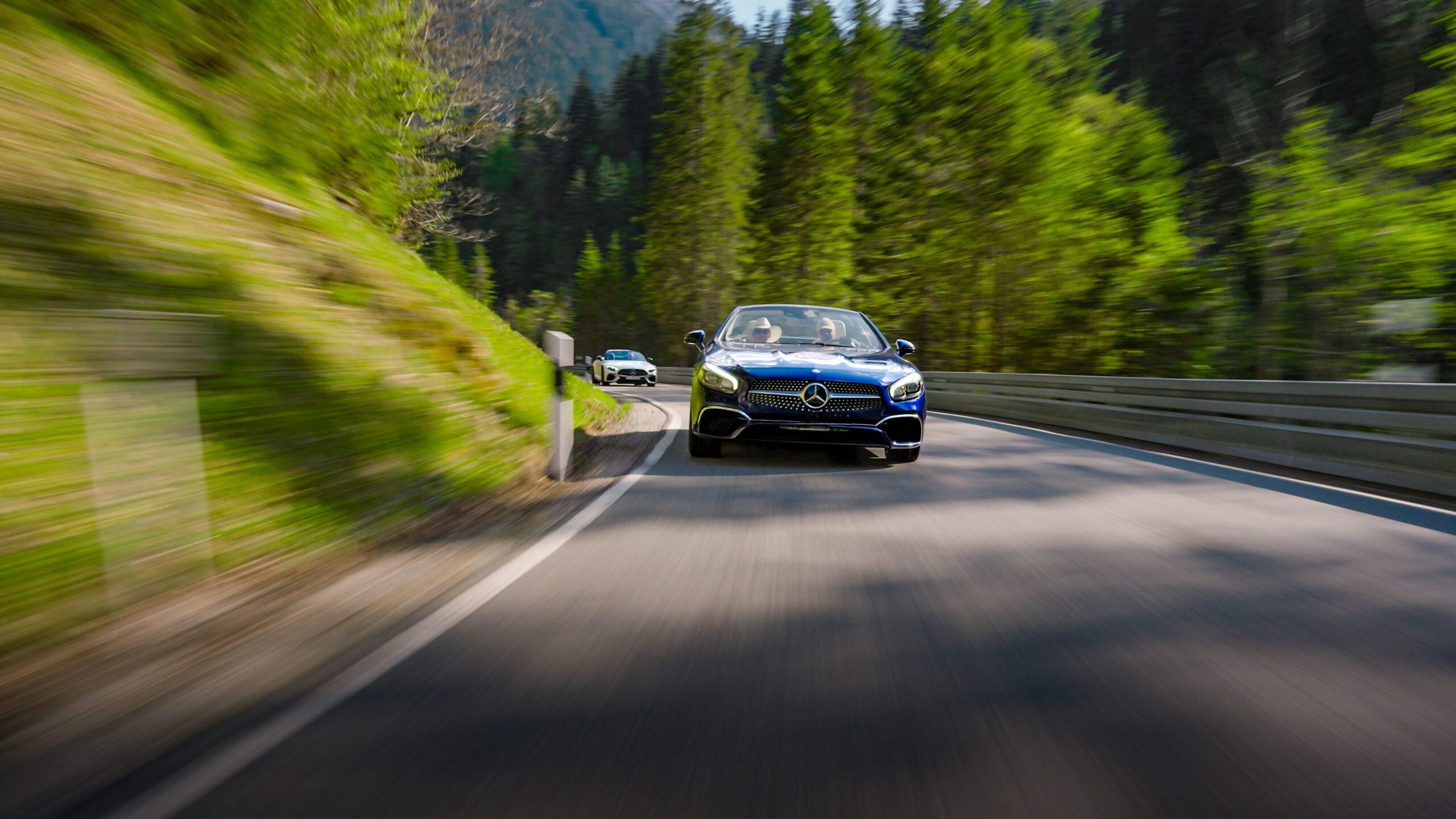 Blauer Sportwagen fährt dynamisch durch kurvigen Waldweg im Schwarzwald.