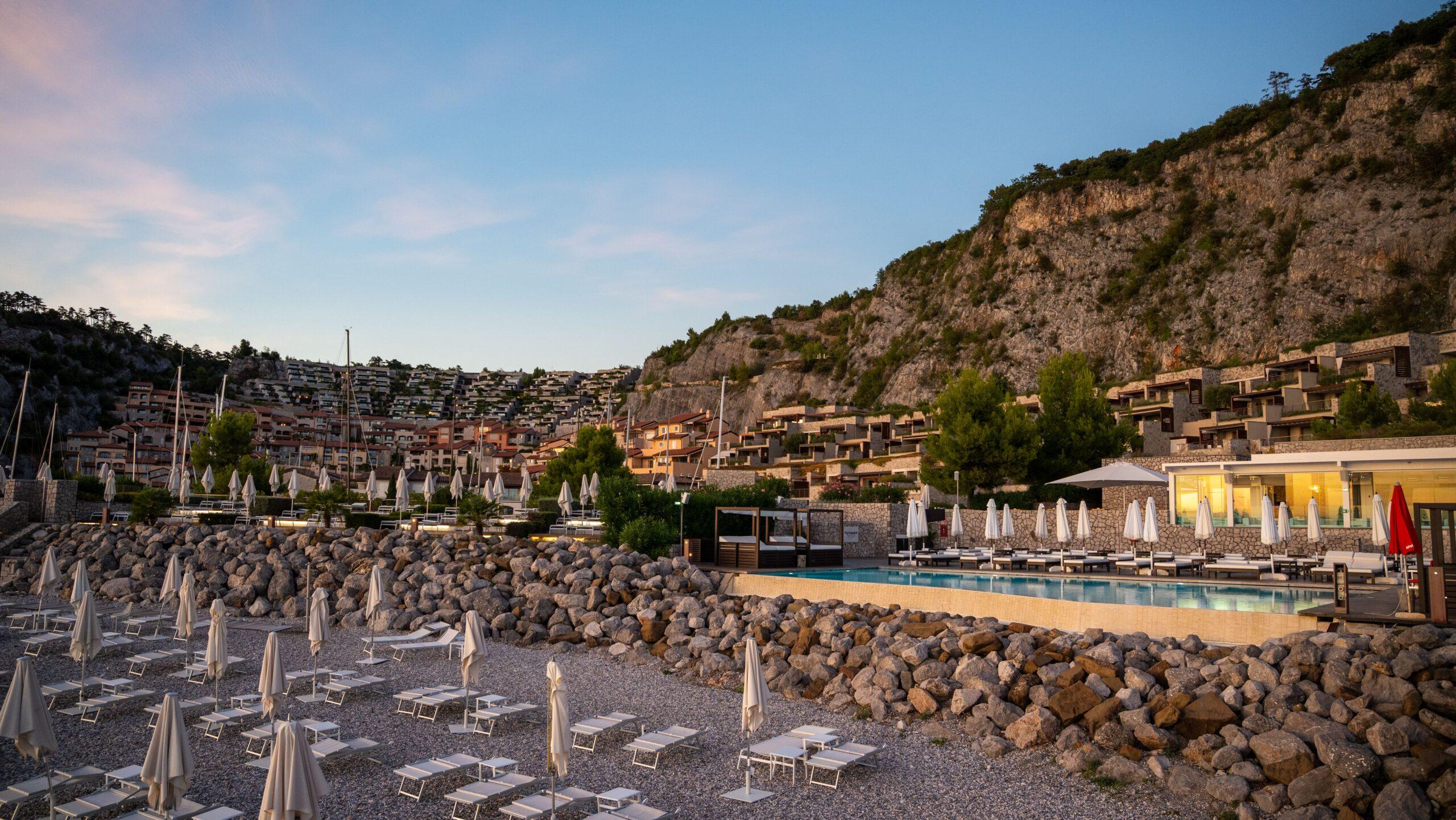 Luxushotel mit Pool und Sonnenschirmen in einer idyllischen Berglandschaft.
