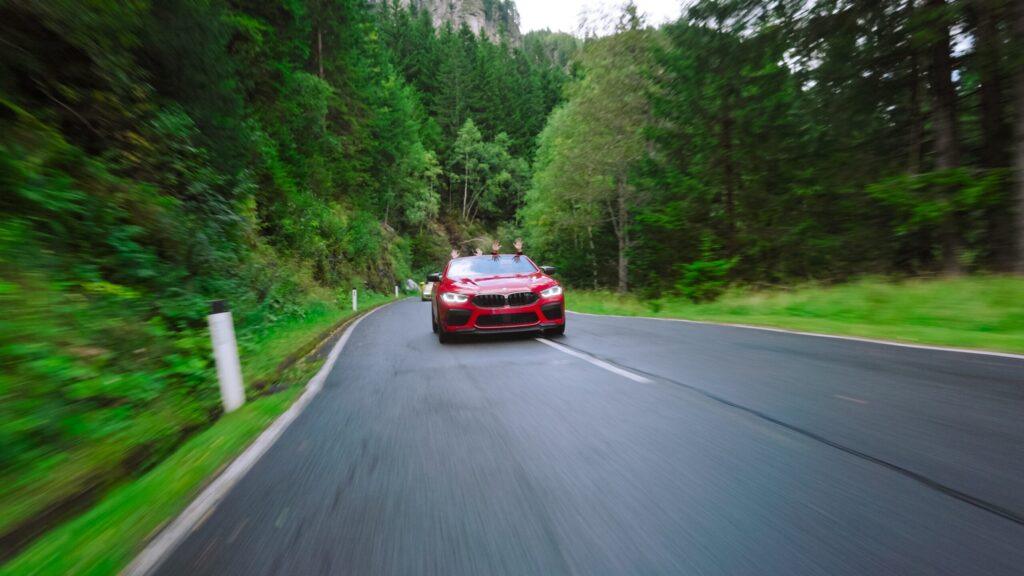 Roter Sportwagen fährt durch malerischen Wald im Schwarzwald. Adrenalinreiche Fahrerlebnisse.