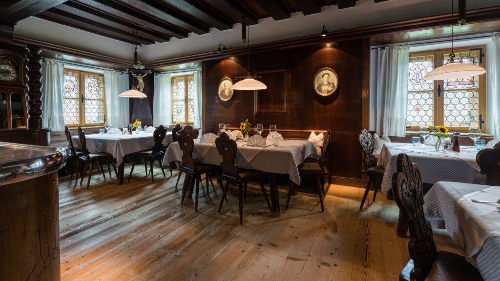 Elegantes Restaurant mit Holzvertäfelung, gedeckten Tischen und Blick auf malerische Fenster.
