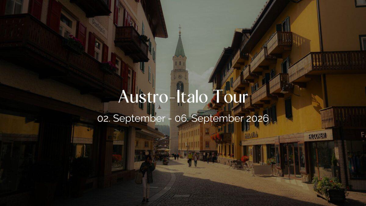 Header Bild der Austro-Italo Tour: Dorfzentrum mit hohem Kirchturm und Gasse in den Alpen.