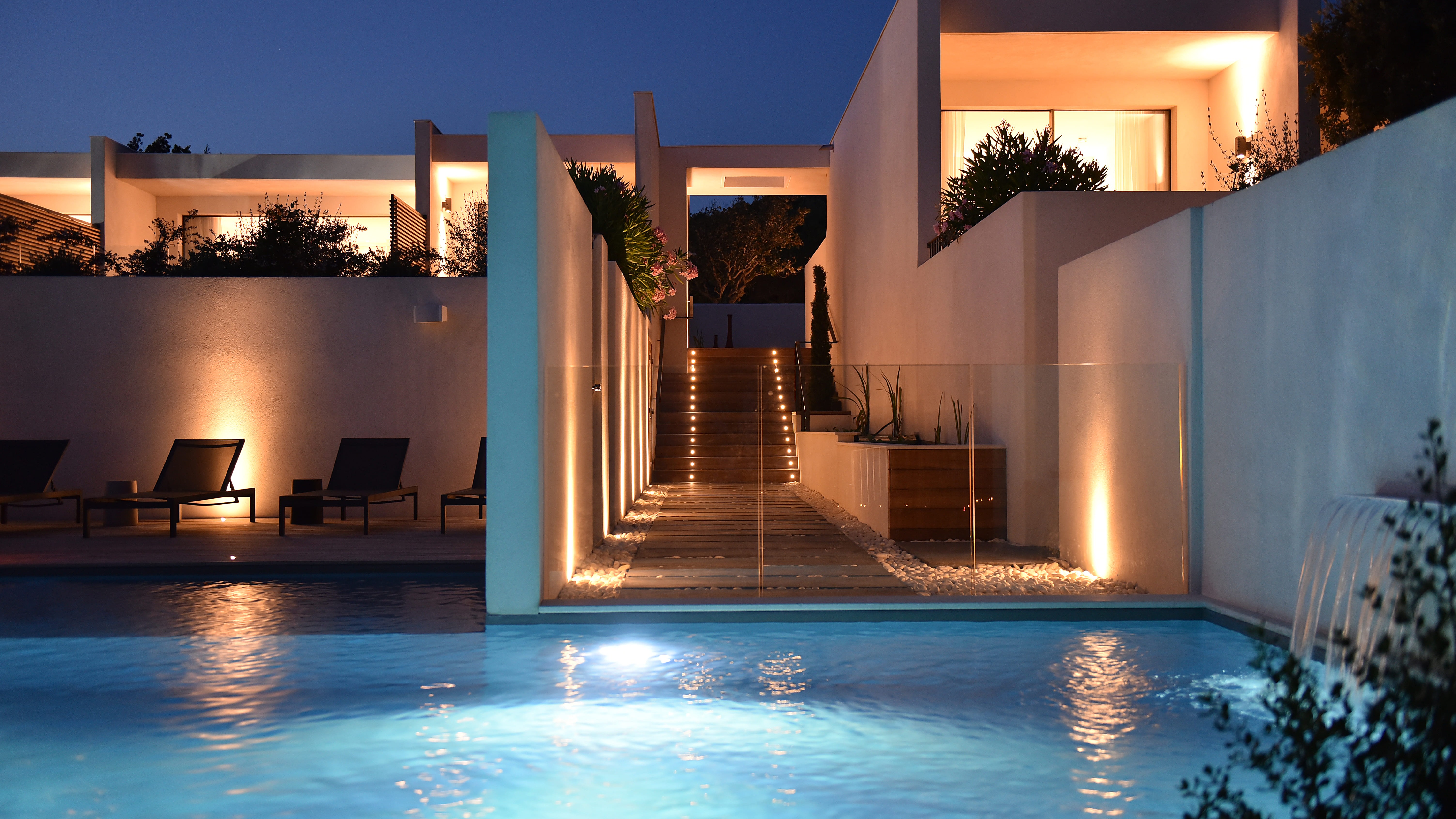 Luxushotel mit beleuchtetem Pool bei Nacht, ideal für Entspannung nach einer Tour.