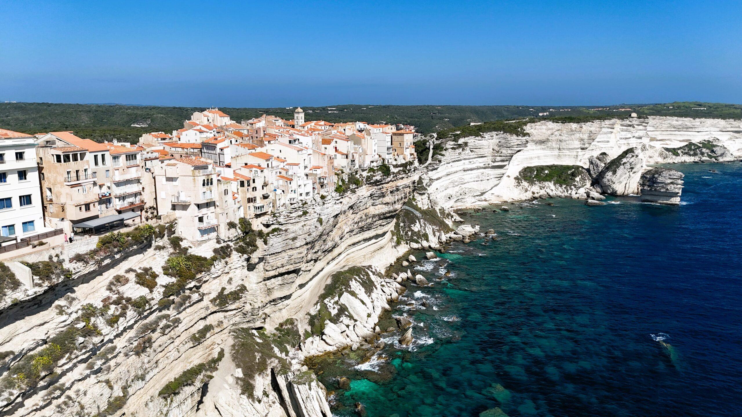 Klippenstadt mit Blick aufs türkisfarbene Mittelmeer unter strahlend blauem Himmel.