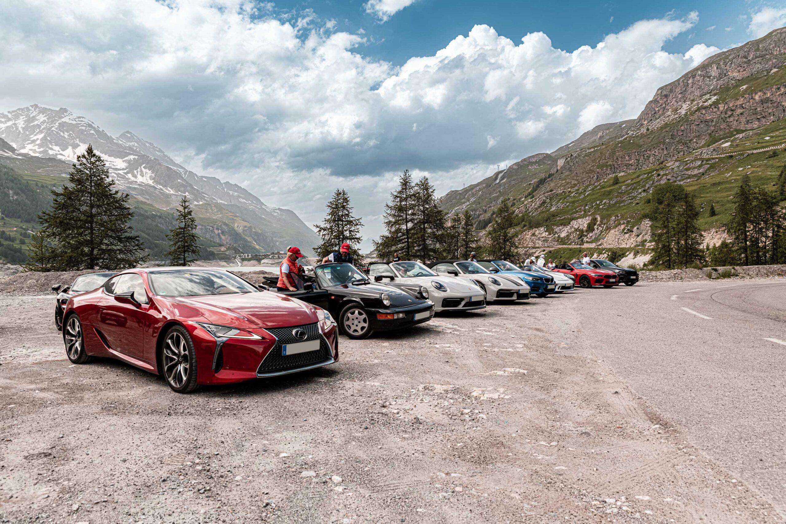 Supercars parken in einer malerischen Alpentour mit beeindruckender Bergkulisse.