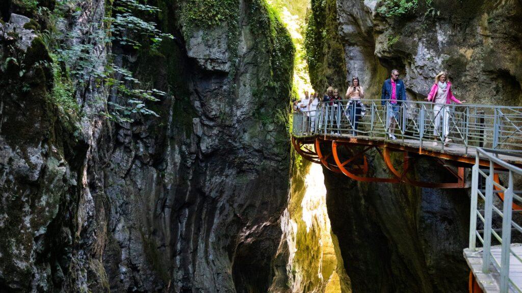 Eine Gruppe von Menschen wandert auf einem Steg durch eine felsige Schlucht.