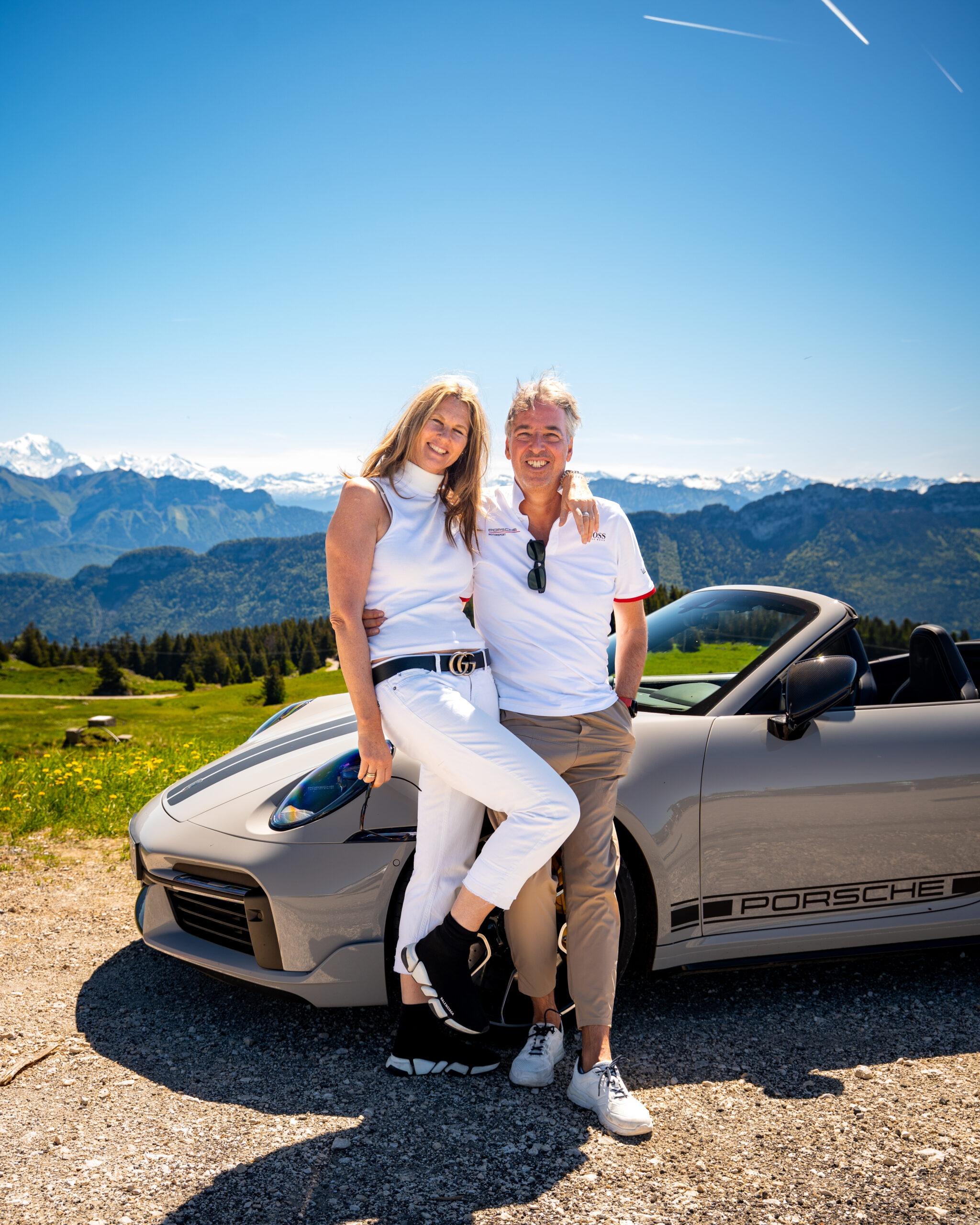 Paar genießt sonnigen Tag mit Porsche vor Alpenpanorama.