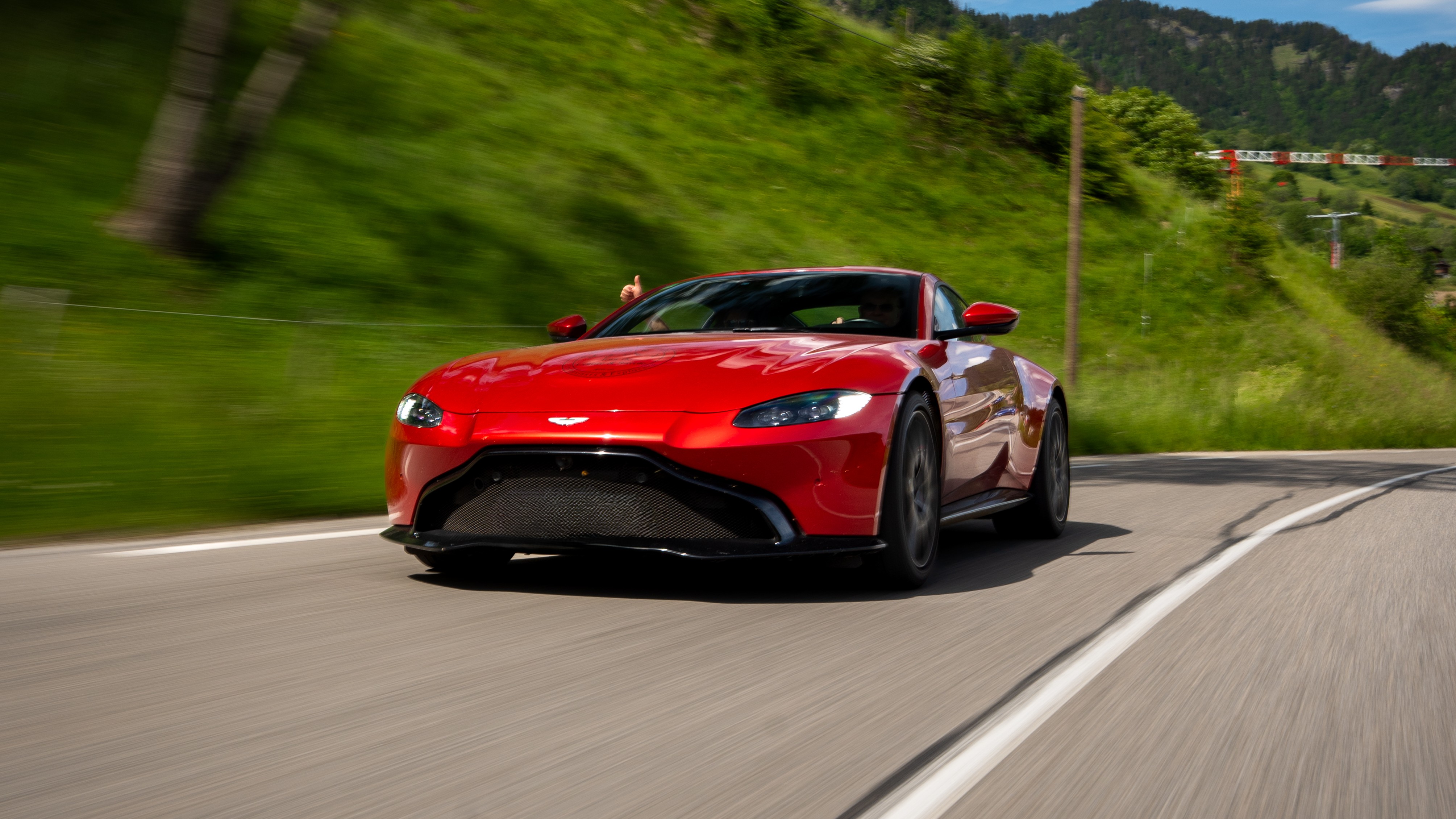 Roter Sportwagen auf kurviger Straße in den malerischen Alpen.