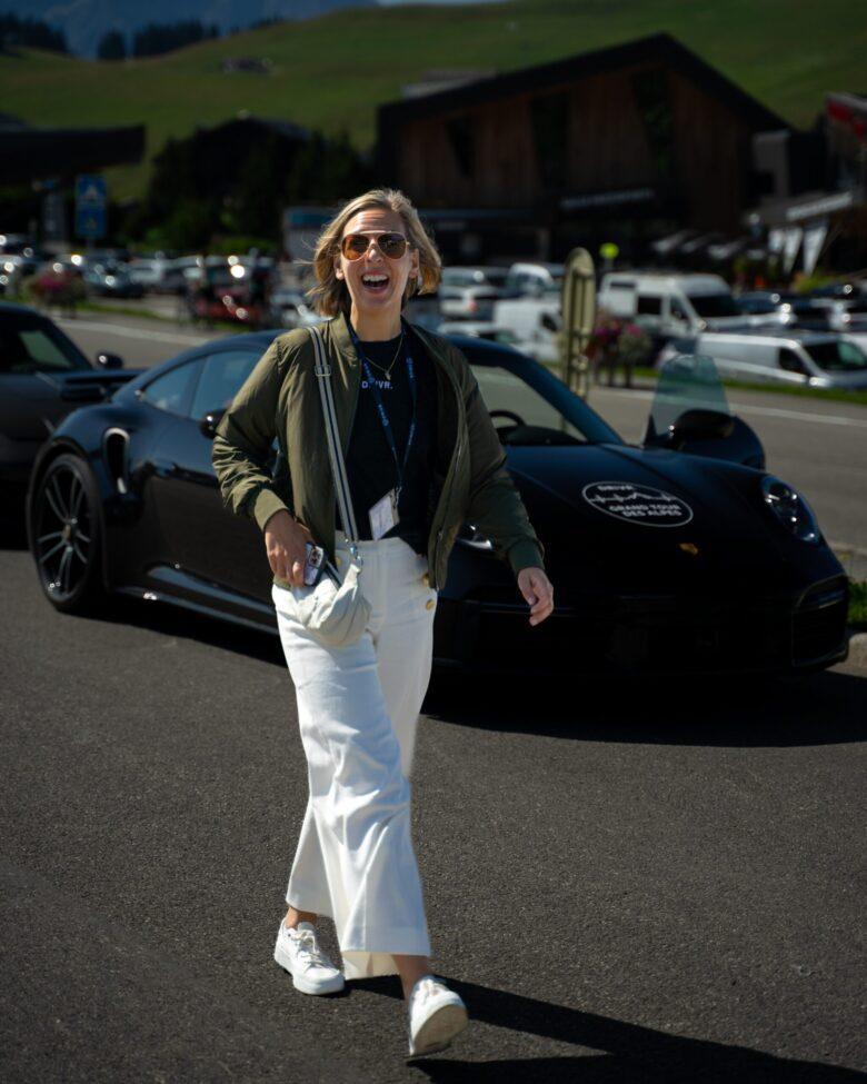 Lachende Kundin neben Porsche bei einer geführten Sportwagen Tour.