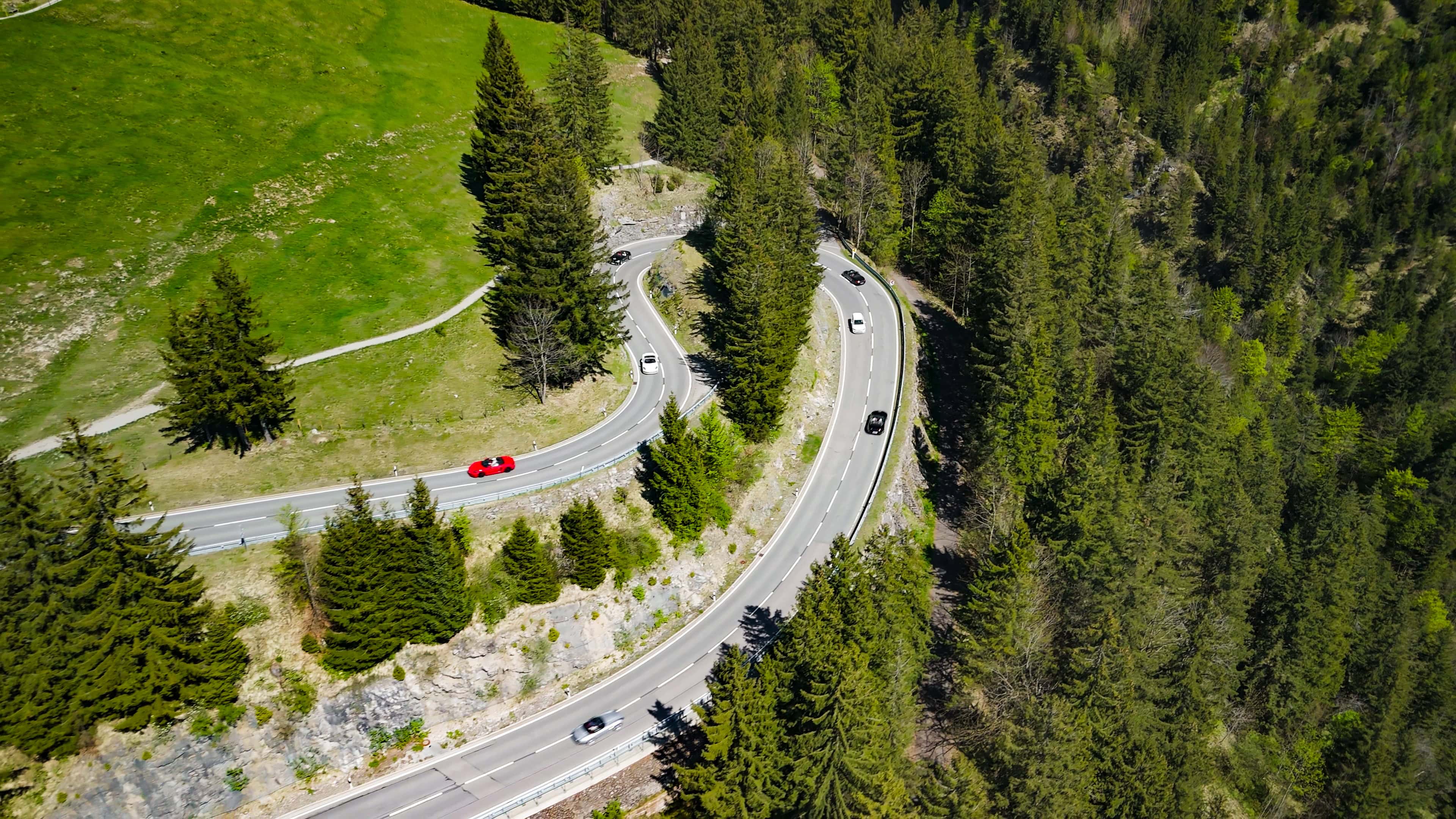 Sportwagen auf kurvenreicher Bergstraße im Schwarzwald, umgeben von üppigen Wäldern.