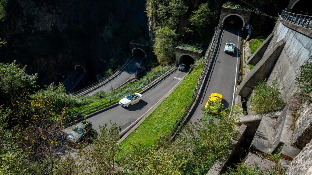 Sportwagen fahren durch beeindruckende Gebirgstunnel in den Alpen.