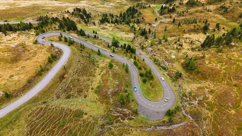 Supercars fahren durch eine kurvenreiche Gebirgsstraße in den Alpen.