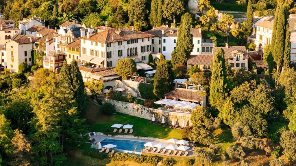 Luxushotel in der Toskana umgeben von grünen Bäumen und Poolbereich.