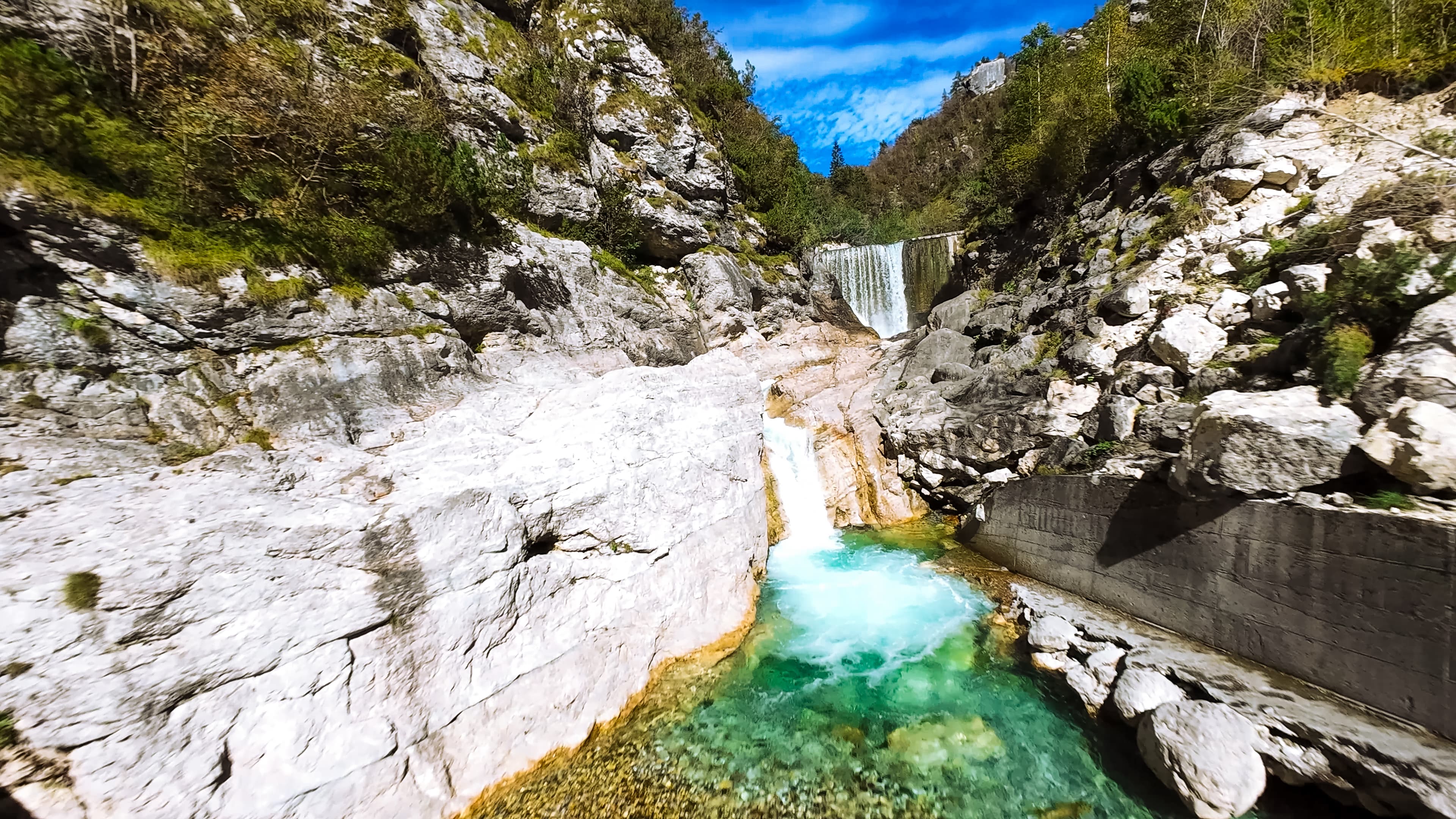 Klares Wasser eines Wasserfalls fließt durch felsige Landschaft in den Alpen.