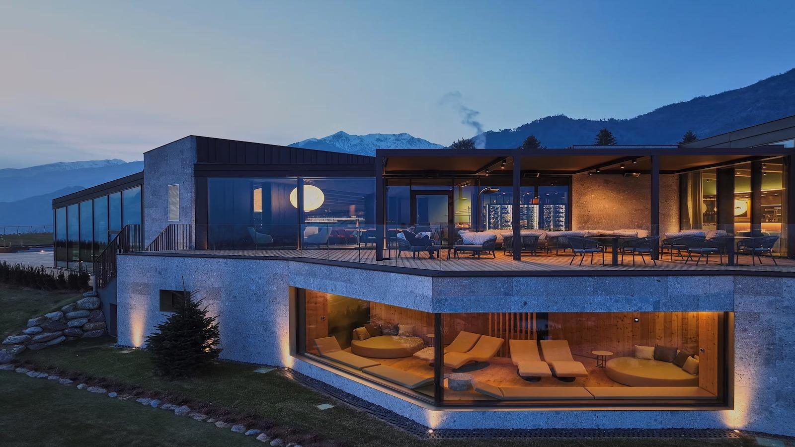 Luxuriöses Hotel in den Alpen mit Bergblick bei Dämmerung.