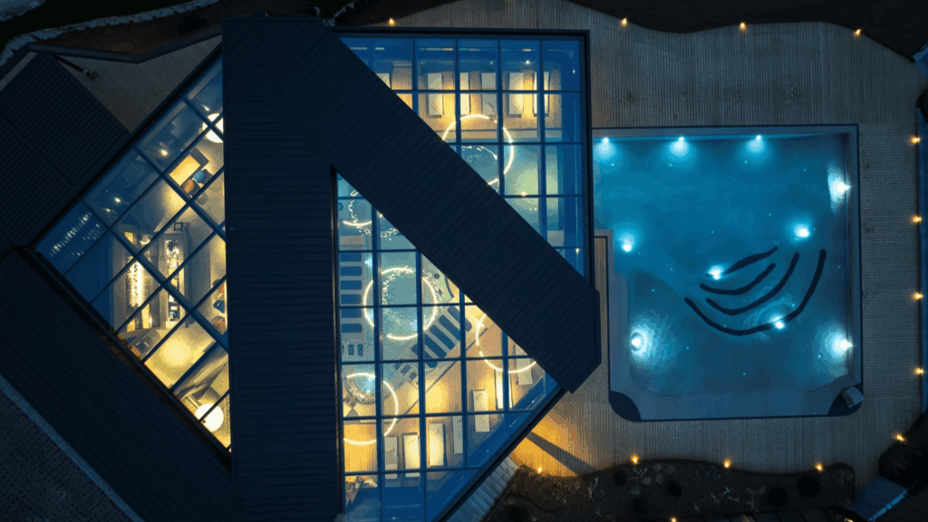 Luftaufnahme eines beleuchteten Luxus-Spas mit angrenzendem Pool bei Nacht.