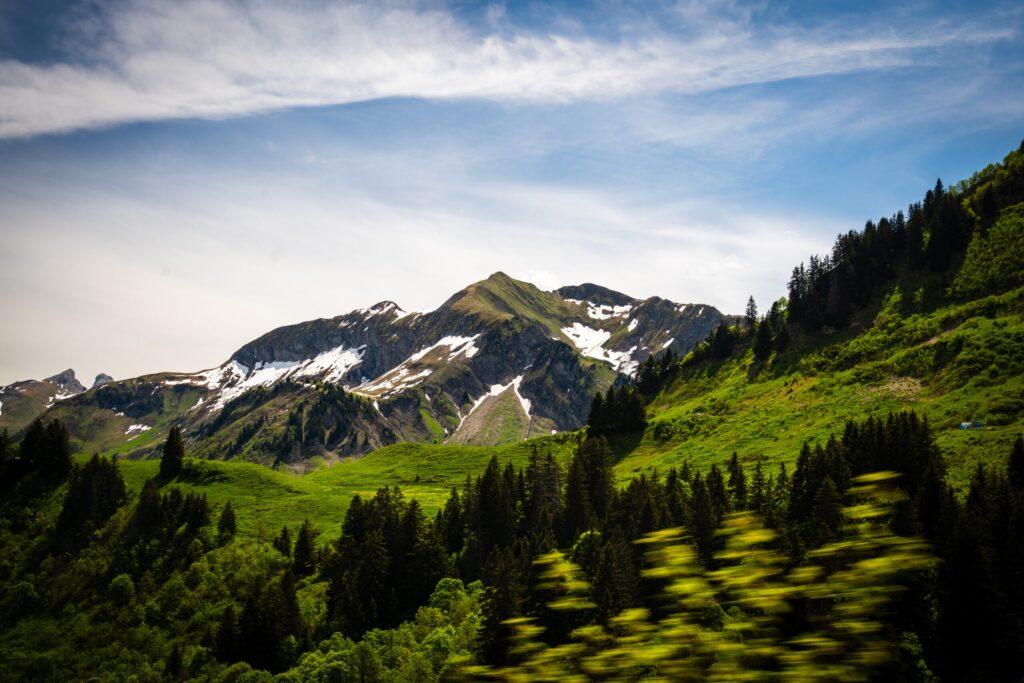 Schneebedeckte Alpen und grüne Täler unter strahlend blauem Himmel.