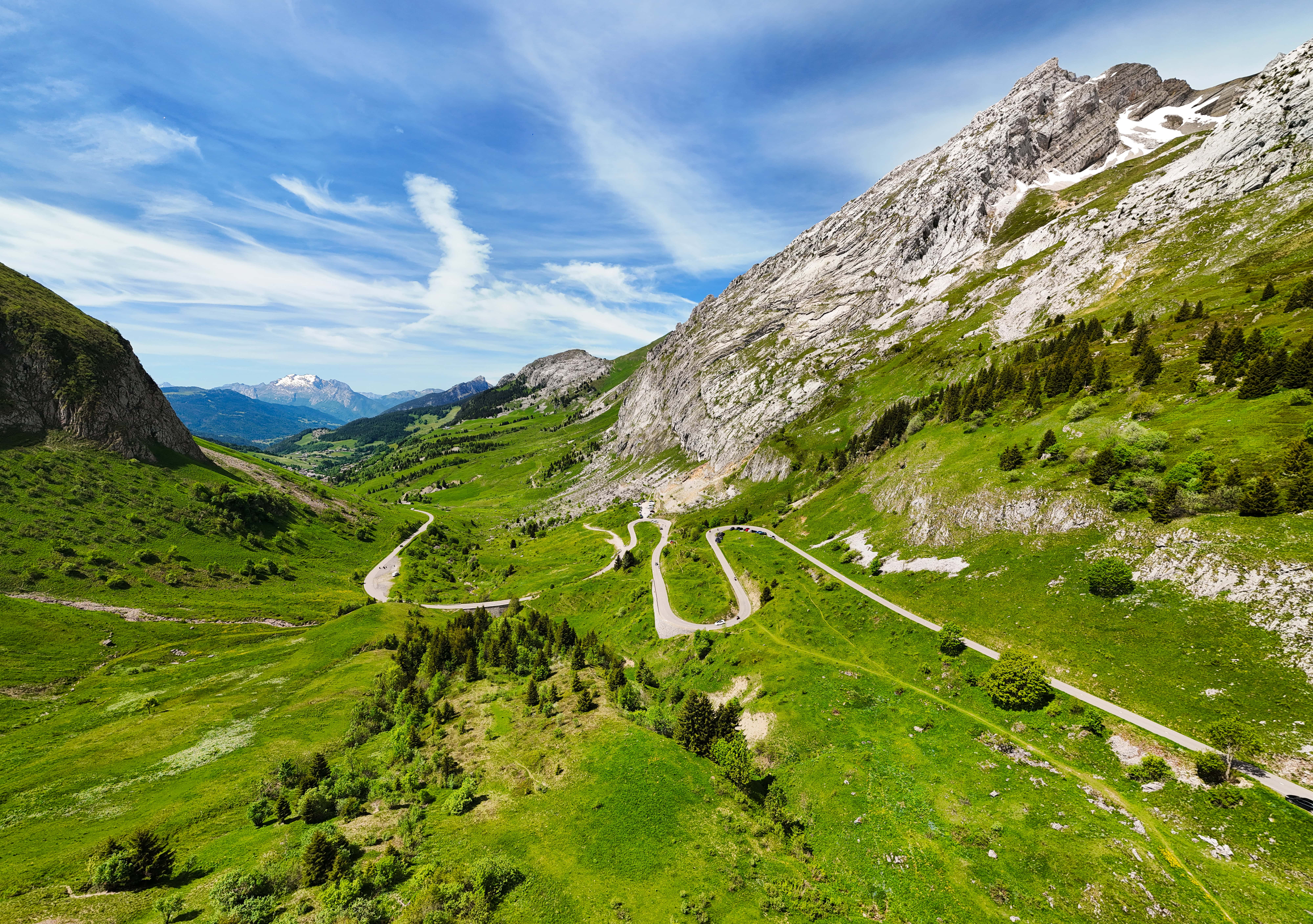 Grüne Tallandschaft mit kurviger Passstraße in der Region Franche-Comté Savoie.