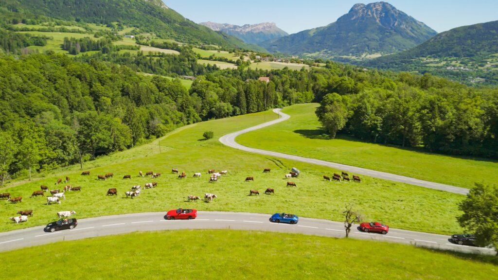 Sportwagen fahren durch idyllische grüne Landschaft in den Alpen.