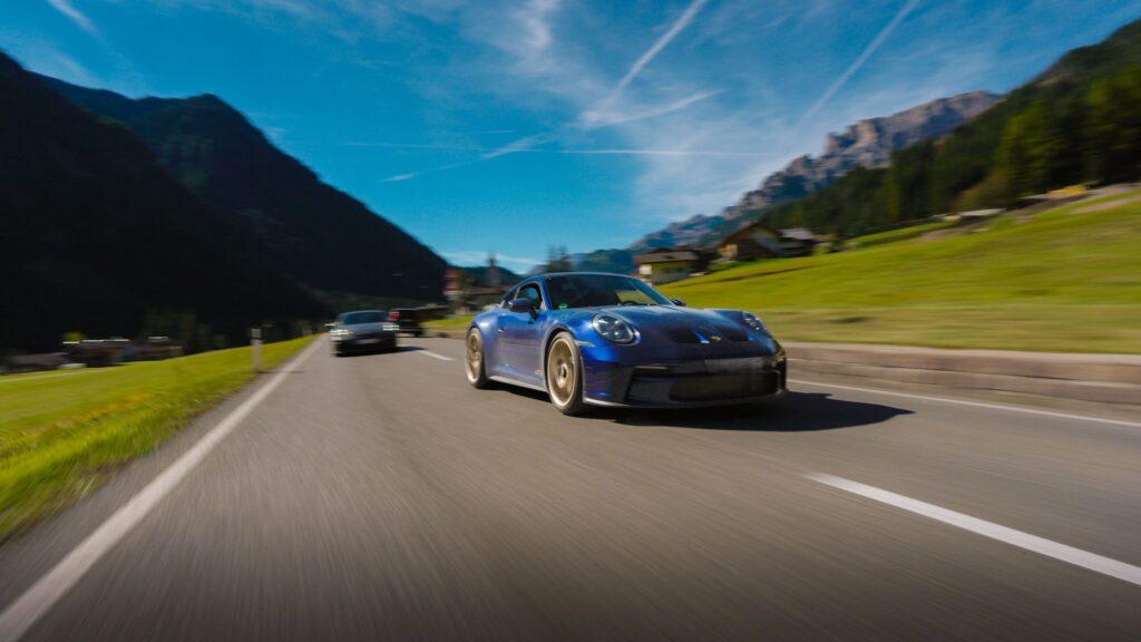 Blaue Sportwagen fahren durch malerische Täler der Dolomiten.