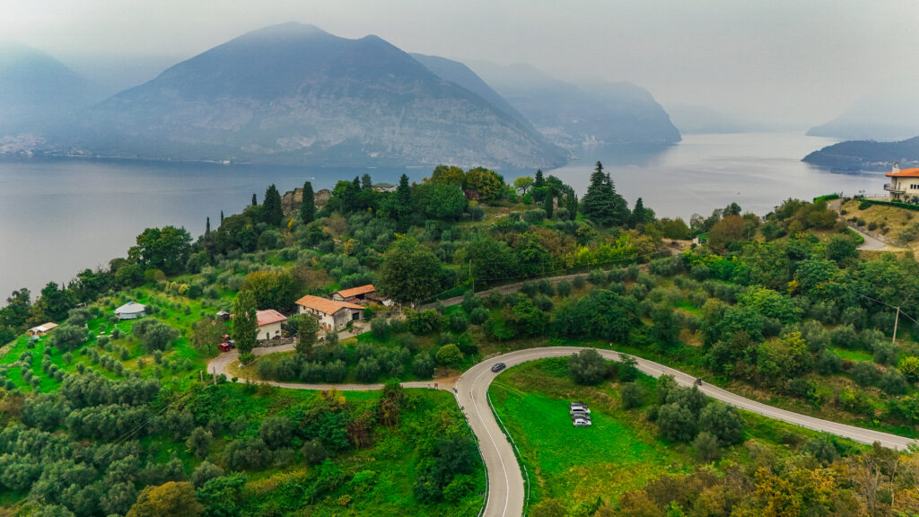 Sportwagen auf kurviger Straße mit Blick auf malerischen See in den Alpen.