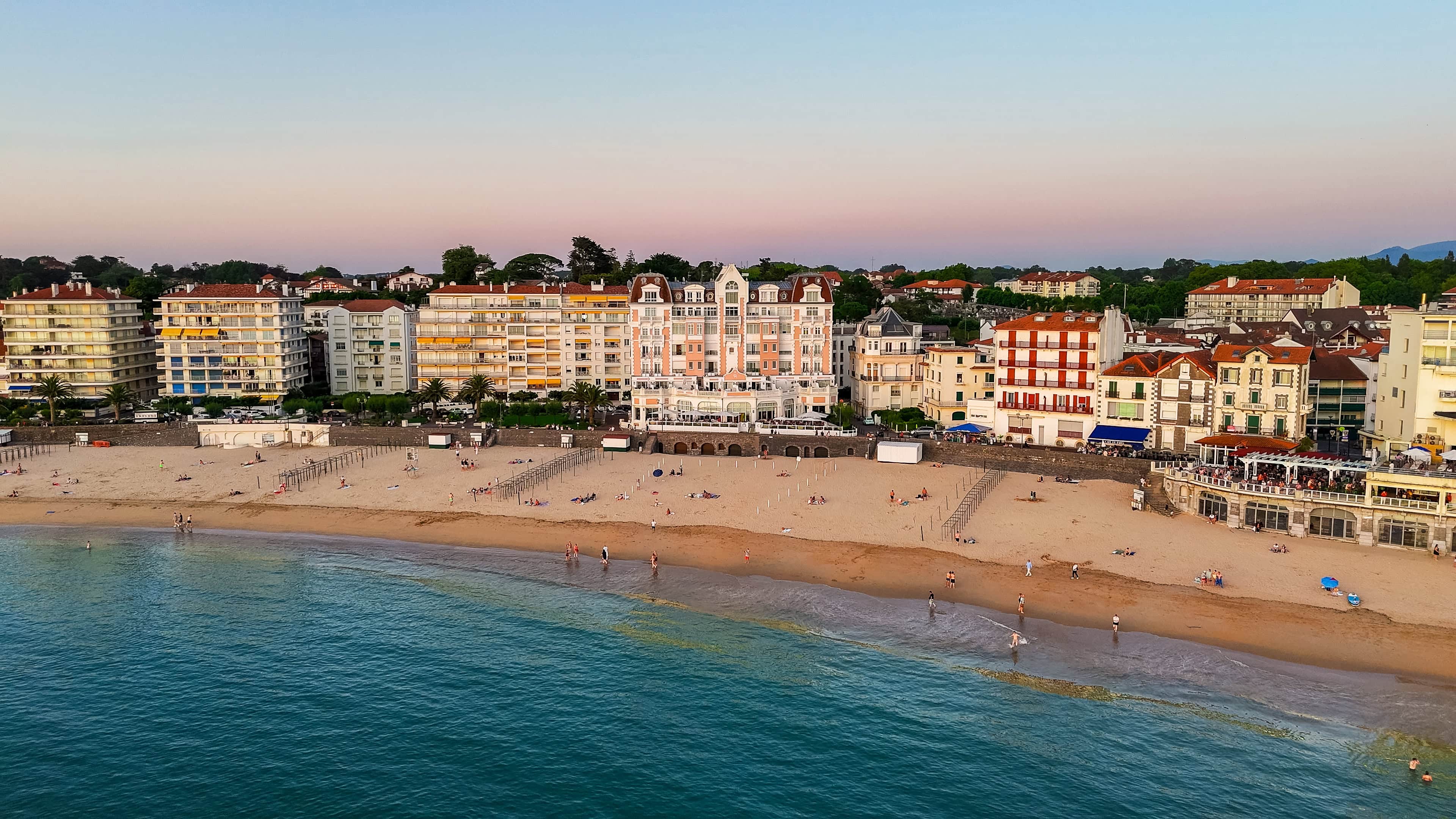 Elegante Strandpromenade mit luxuriösen Hotels und Gästen bei Sonnenuntergang in Biarritz.