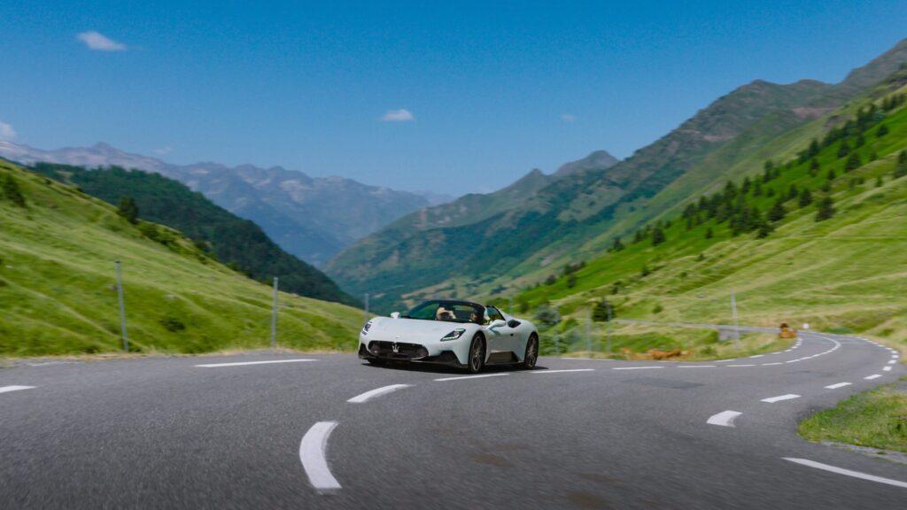 Ein eleganter Sportwagen kurvt auf einer malerischen Bergstraße in den Alpen. Die grüne Landschaft strahlt Freiheit und Abenteuer aus.