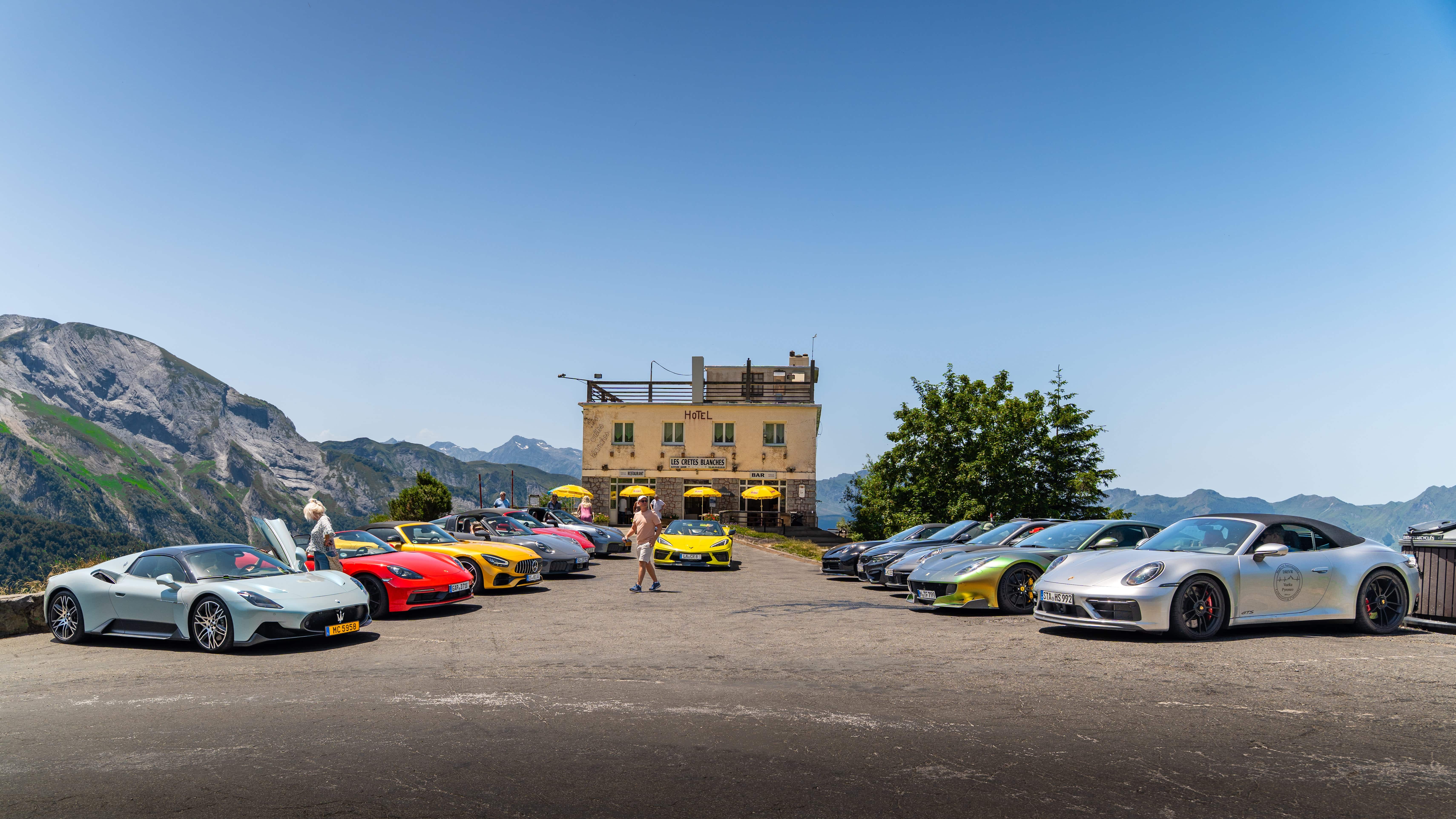 Luxuriöse Sportwagen in den Alpen vor einem malerischen Hotel mit Bergpanorama.