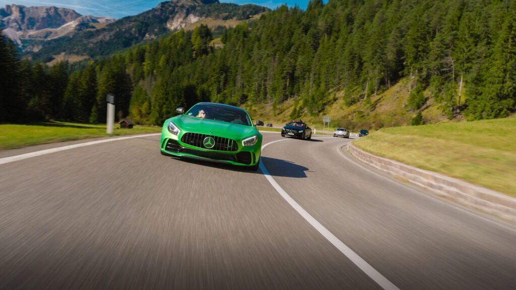 Grüne Sportwagen fahren durch malerische Bergstraßen in den Dolomiten.