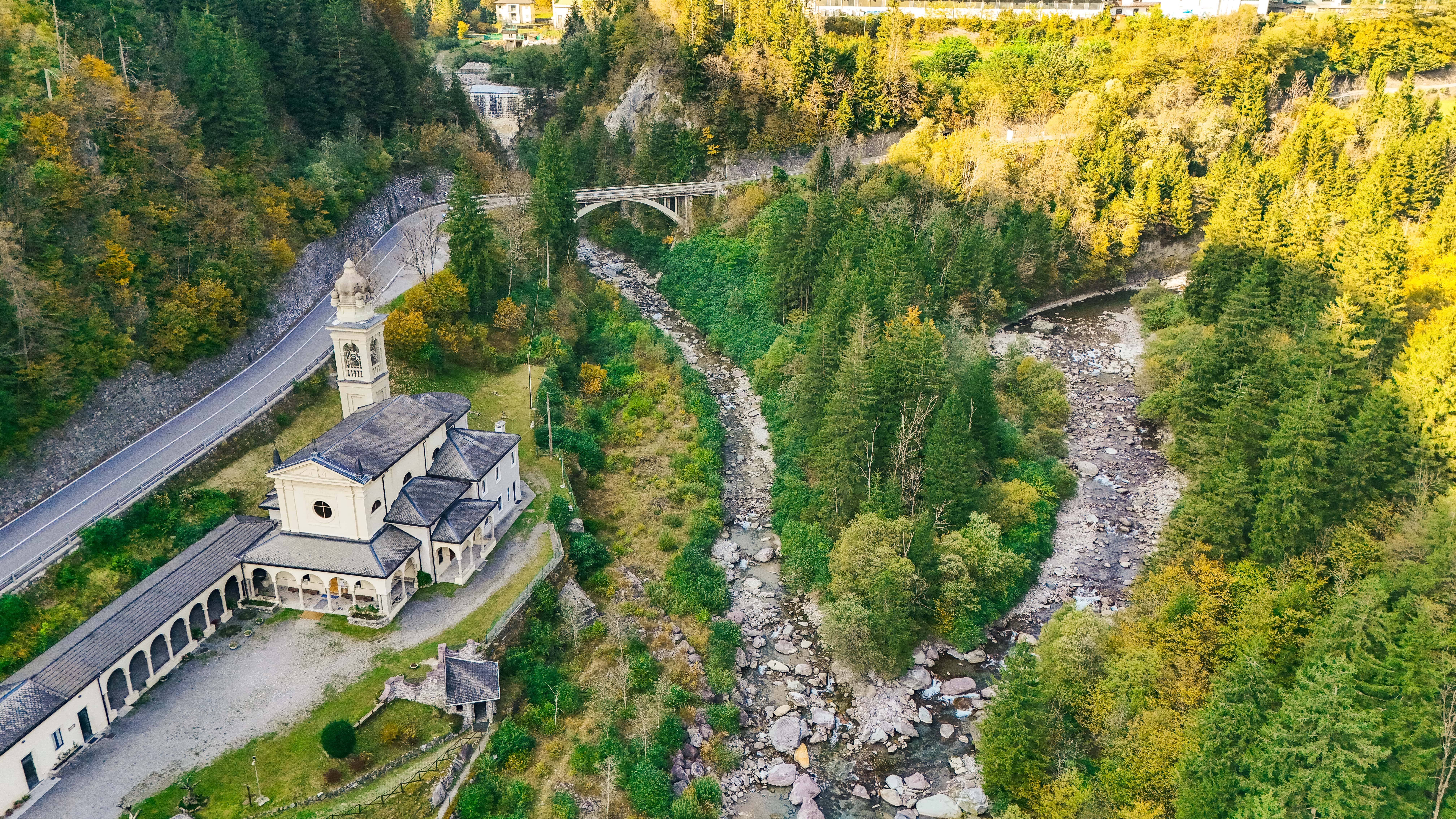 Luftaufnahme einer malerischen Kirche an einer kurvenreichen Straße in den Dolomiten.
