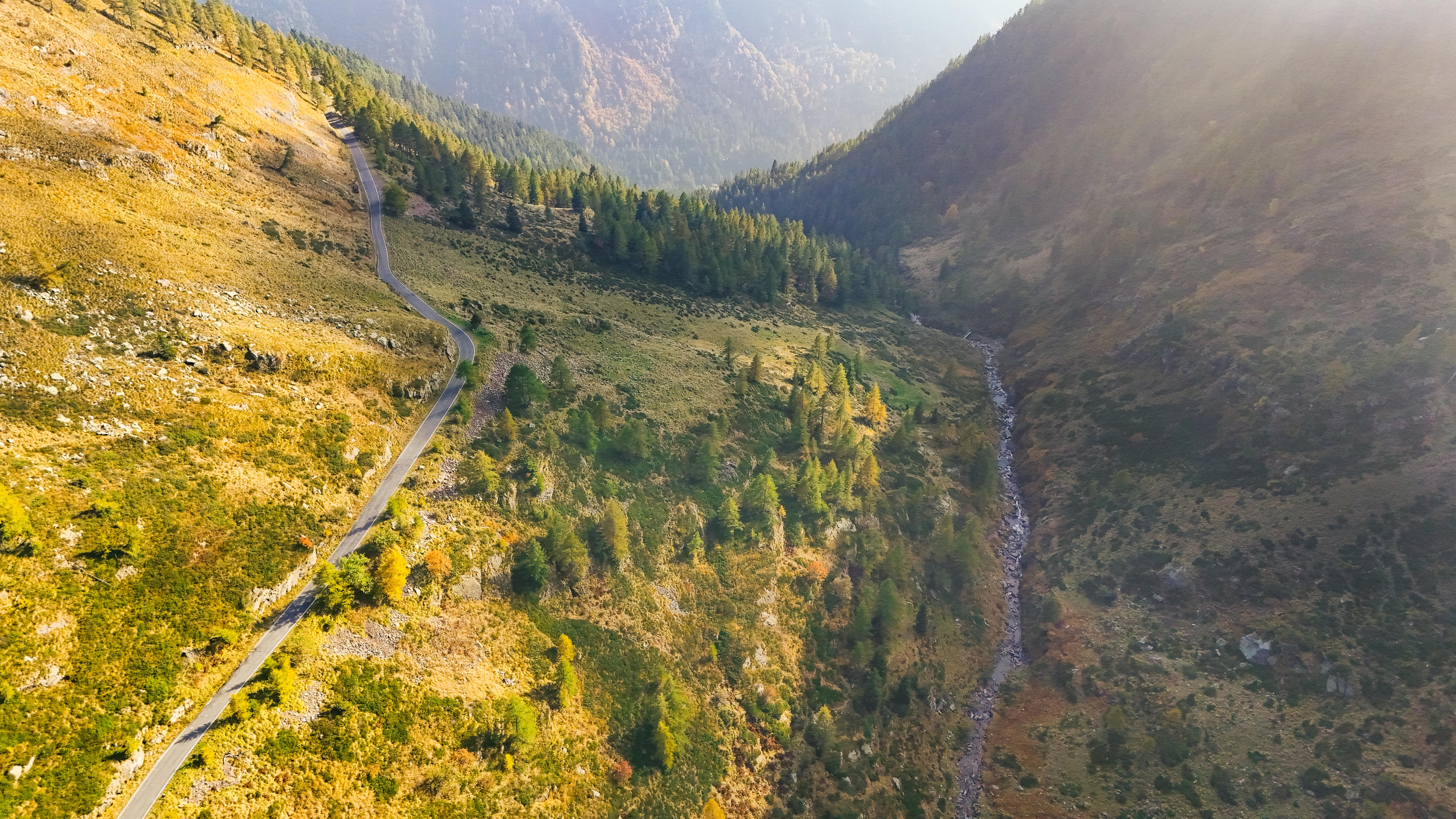 Serpentinenstraße durch die Alpen mit malerischer Landschaftsaufnahme aus der Luft.