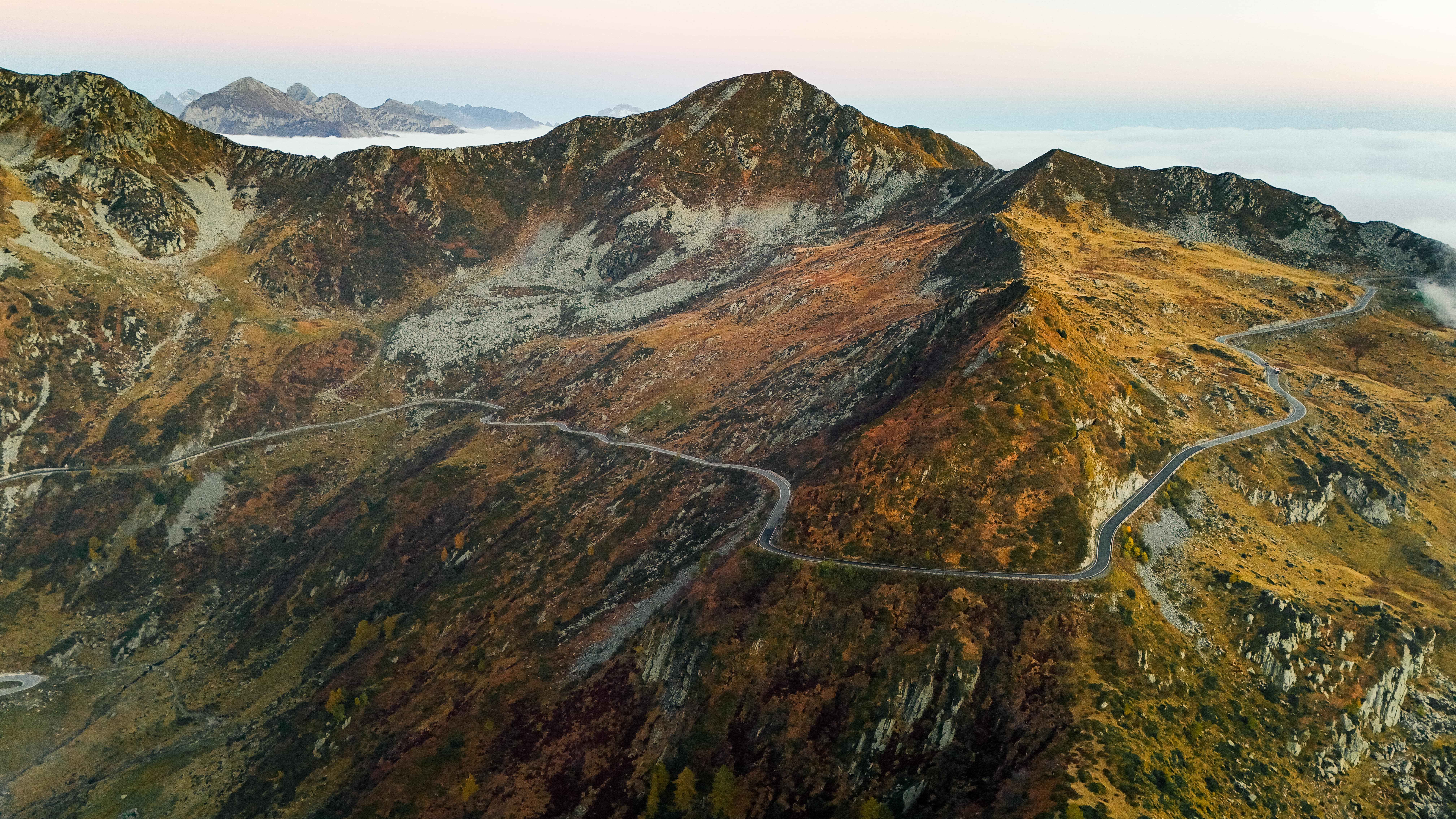 Serpentinenstraße in den Alpen bei Sonnenuntergang, perfekte Route für Sportwagen.