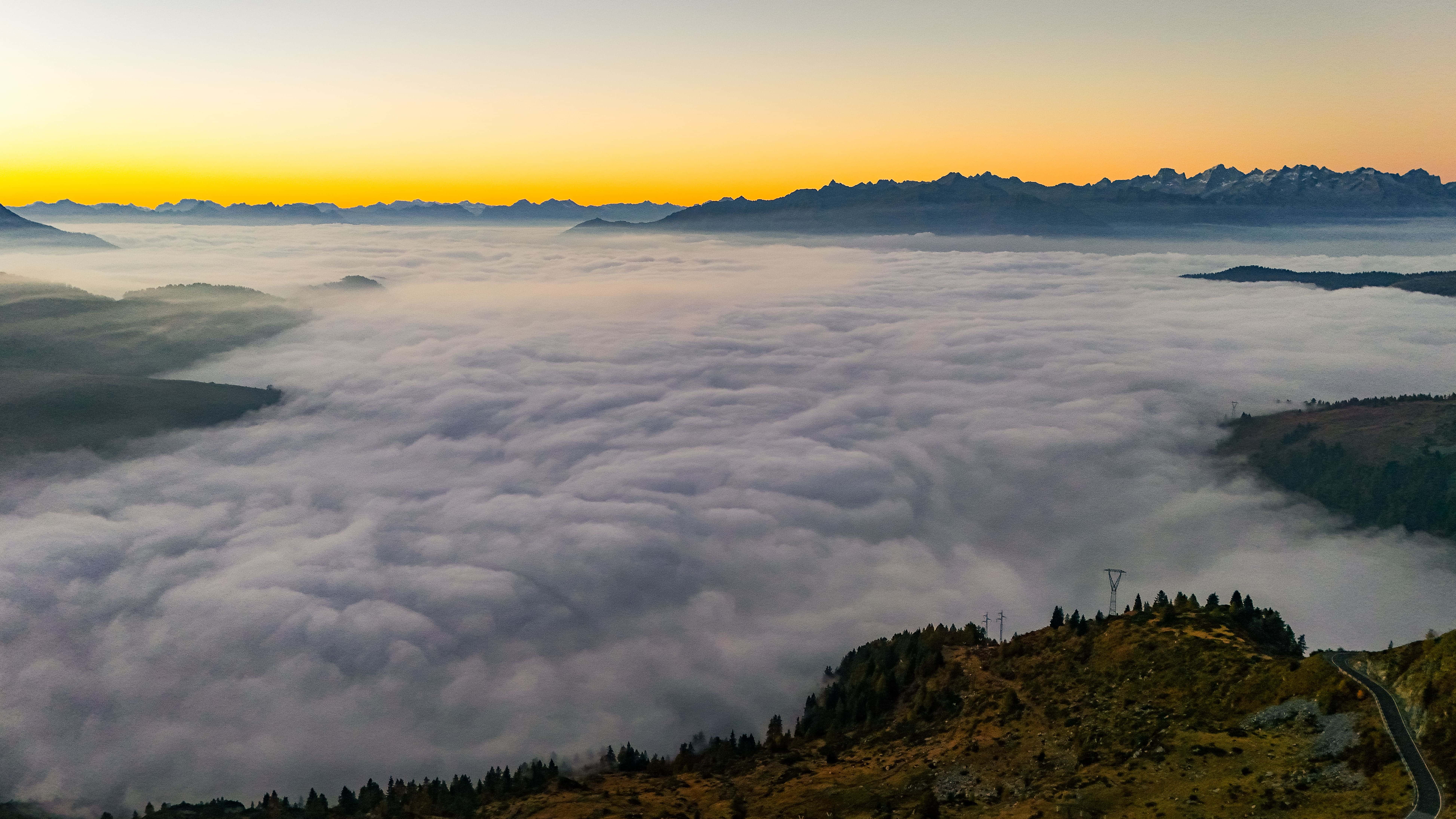 Blick über die Wolkenmeer in den Alpen, umgeben von majestätischen Bergen und warmen Sonnenstrahlen.