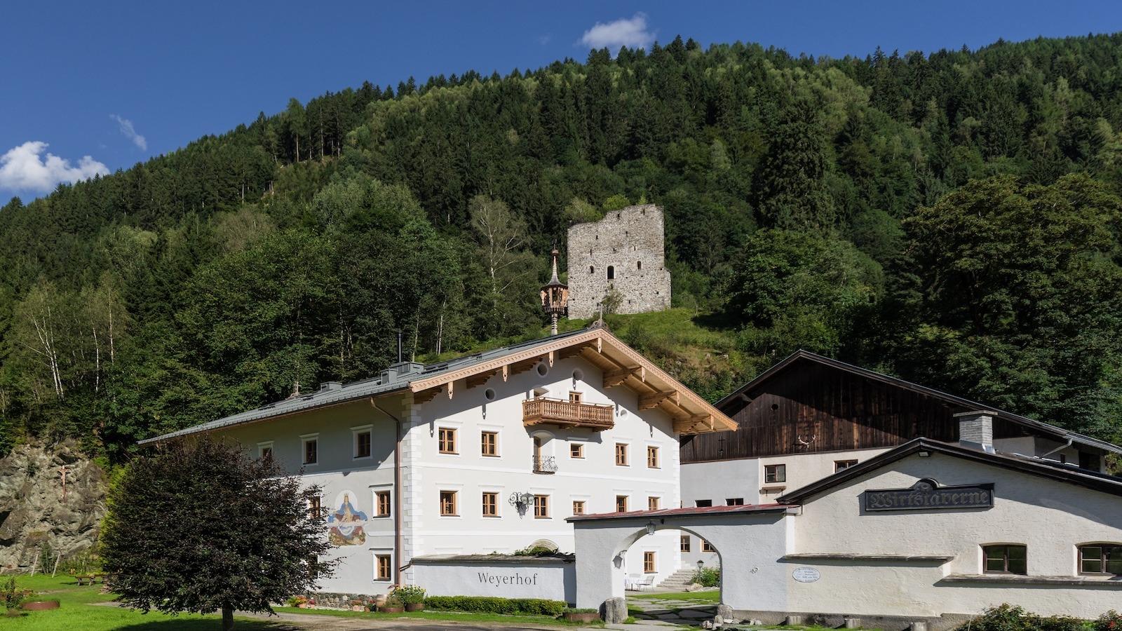 Altes Gasthaus in den Alpen vor malerischer Bergkulisse und grünen Wäldern.