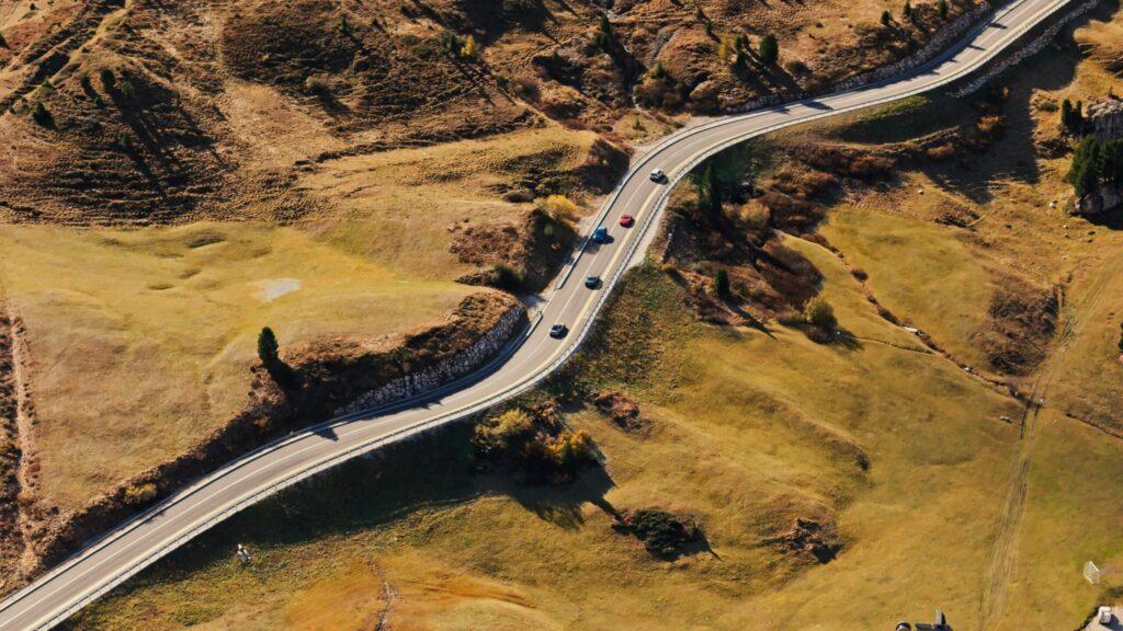 Kurvenreiche Straße durch traumhafte Landschaften, umgeben von sanften Hügeln und herbstlichen Farben.