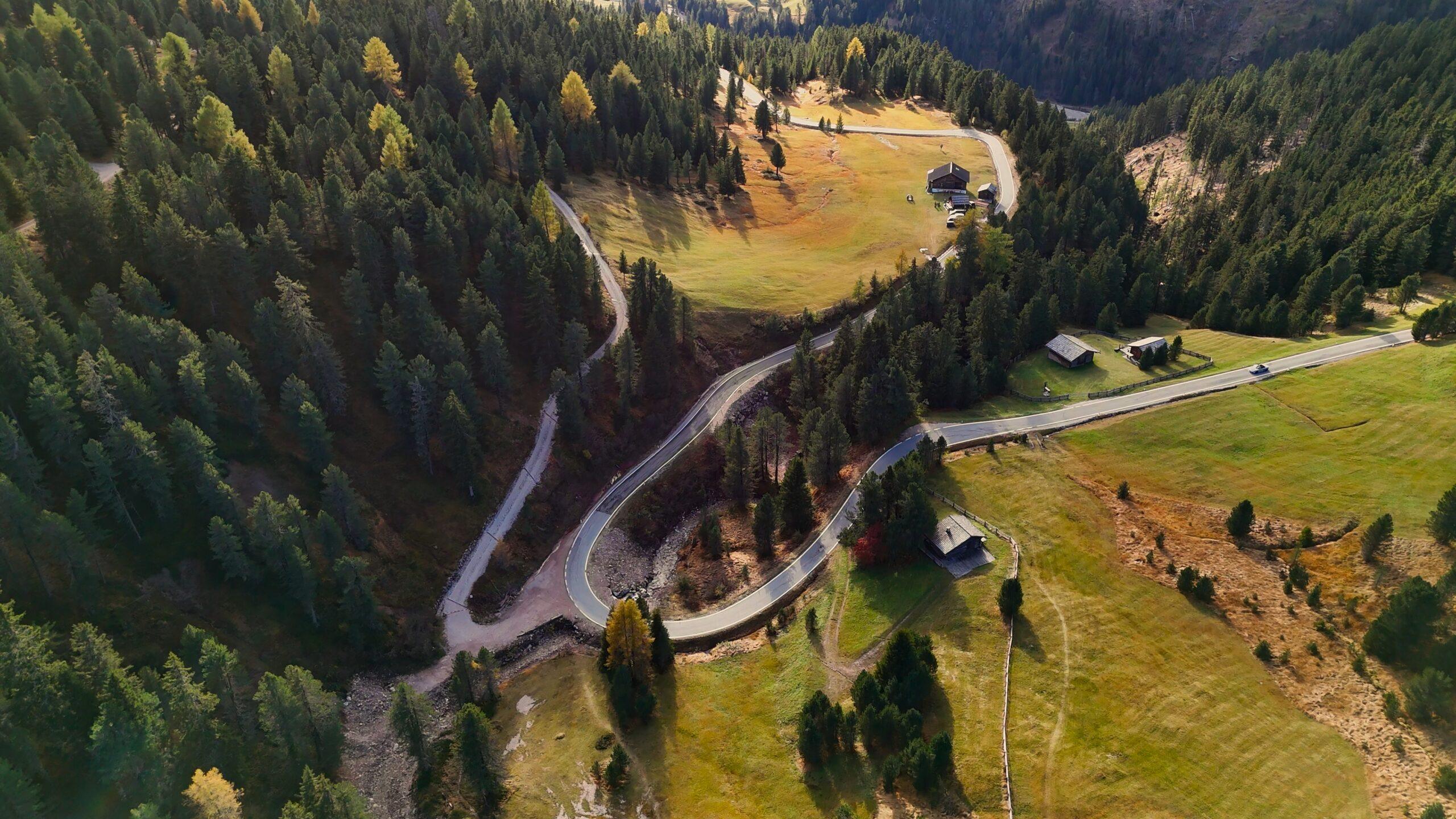 Windende Straße zwischen saftigen Wäldern und malerischen Wiesen in den Alpen. Ideal für unvergessliche Cabriofahrten.