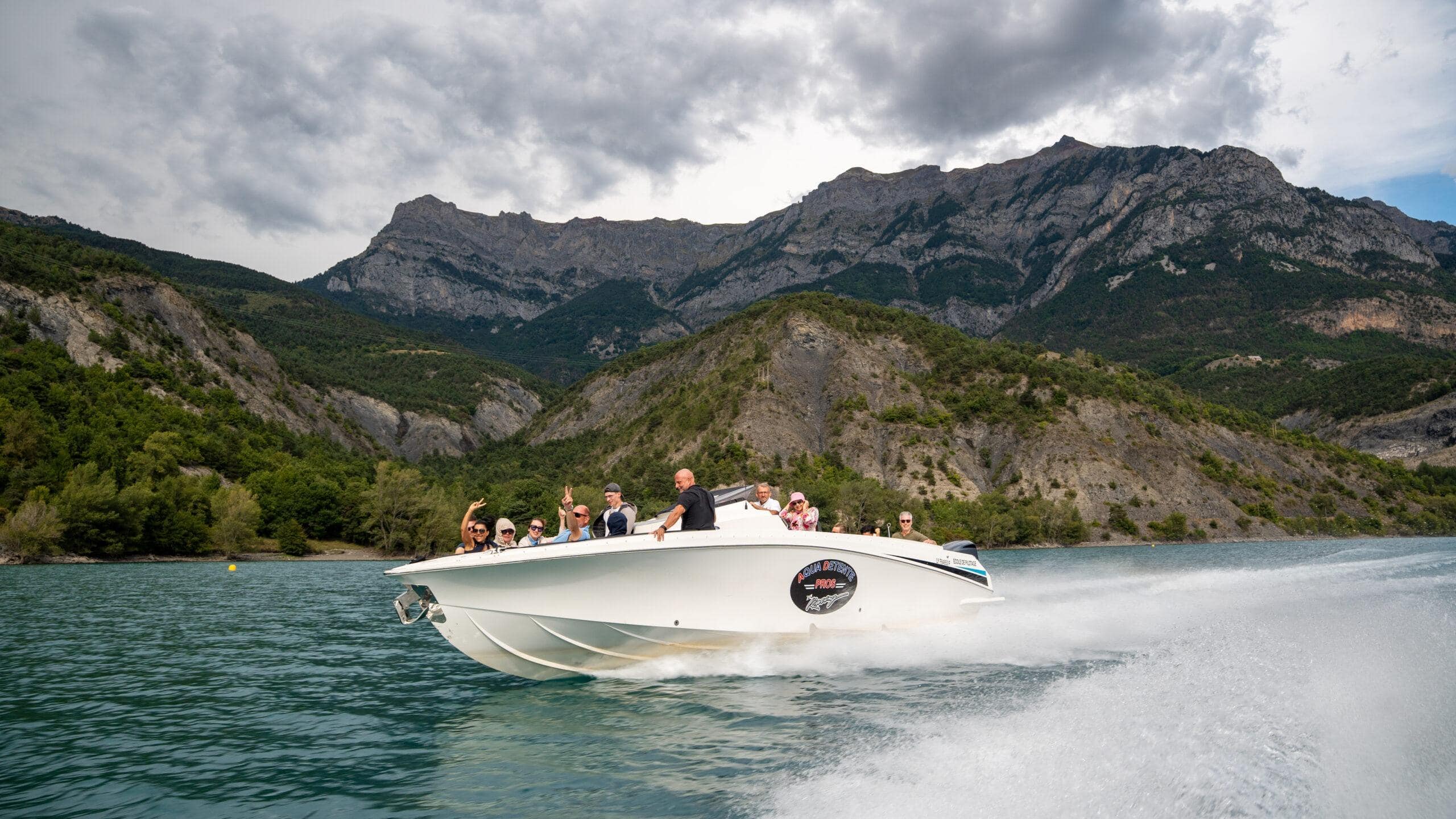 Schnelle Bootstour auf einem glitzernden See, umgeben von majestätischen Bergen und grüner Natur.