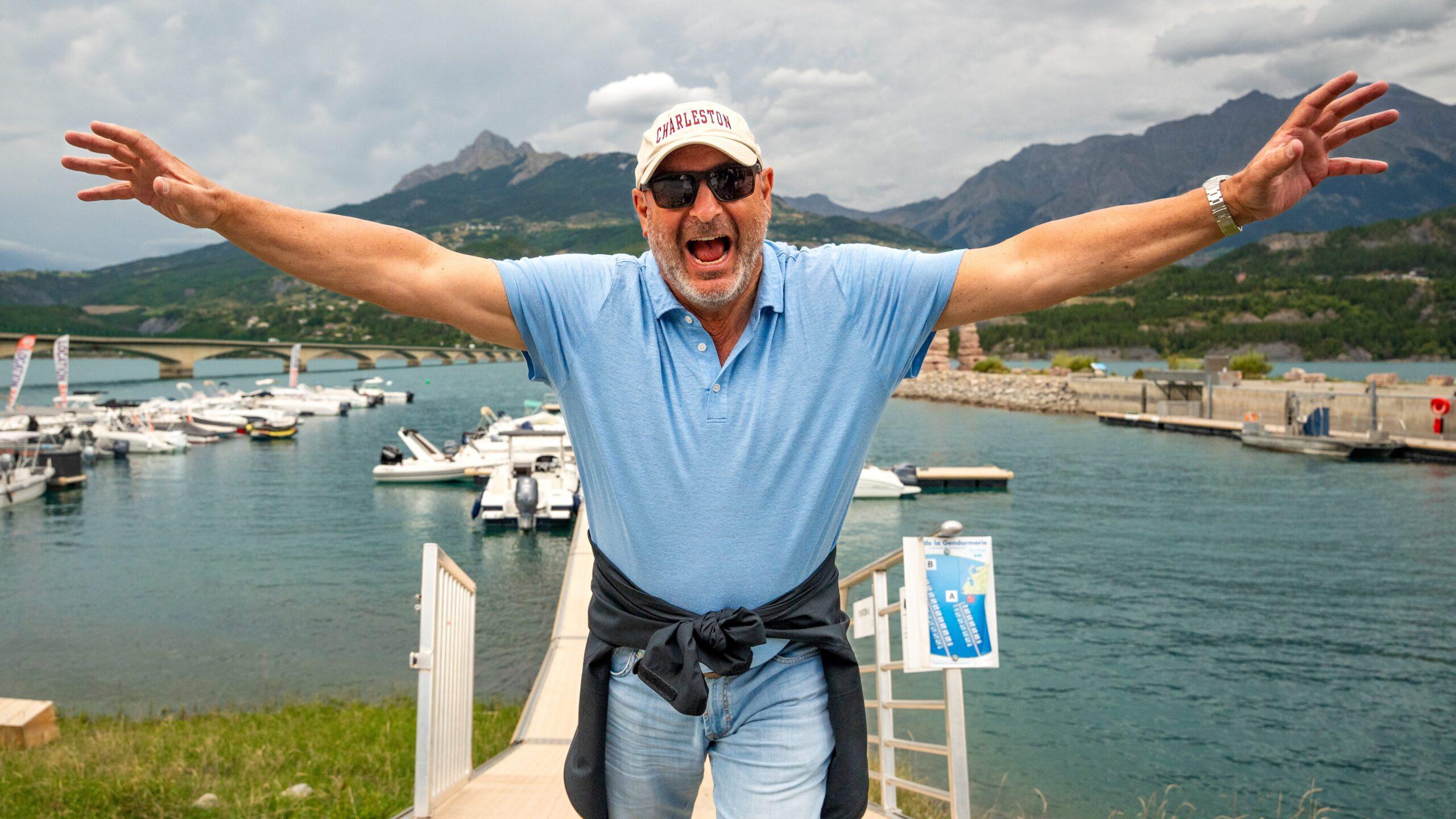 Eine Person freut sich am Ufer mit einer spektakulären Bergkulisse im Hintergrund.