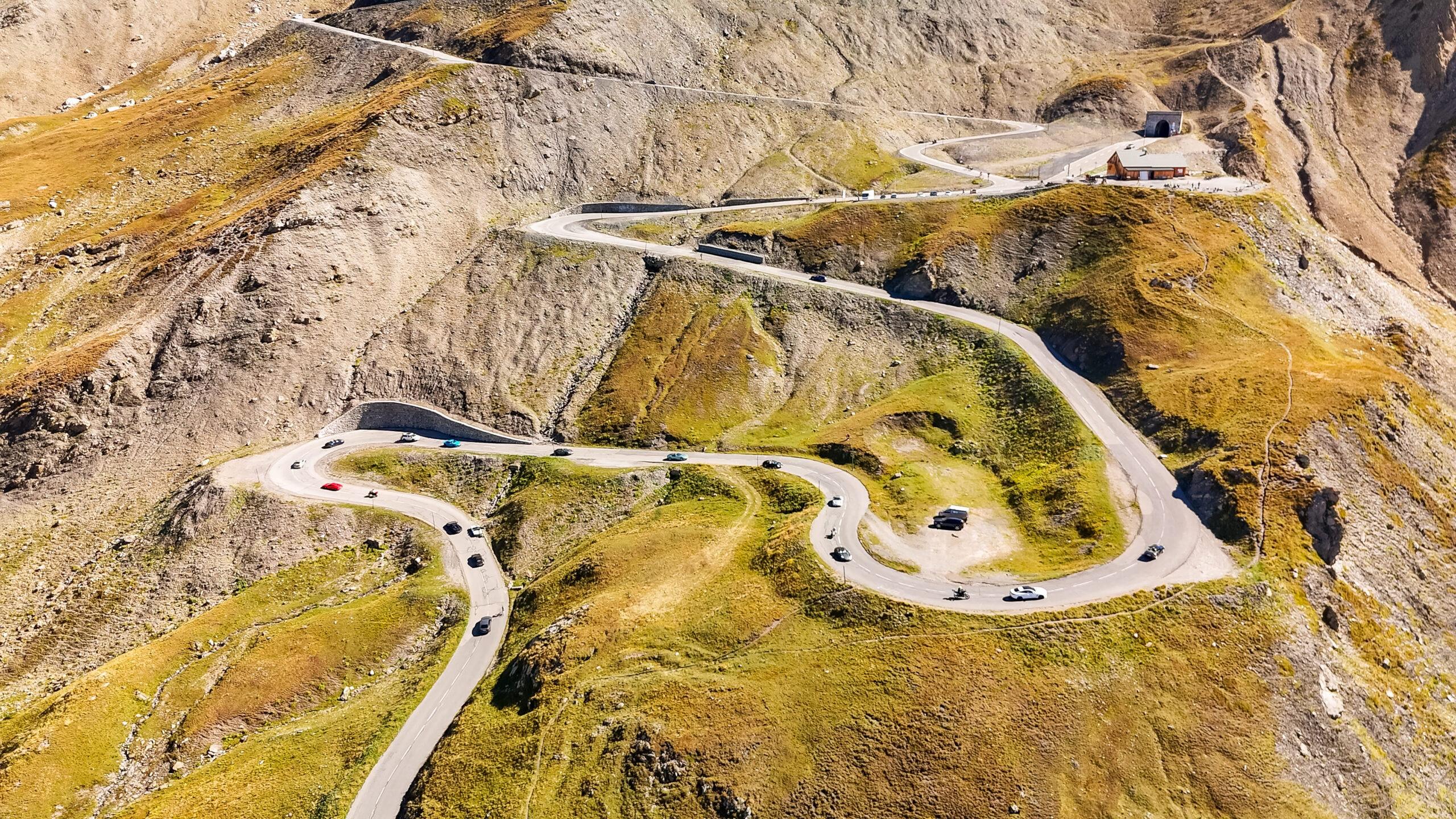 Supercars fahren durch atemberaubende Alpenstraßen voller Kurven und Landschaften.