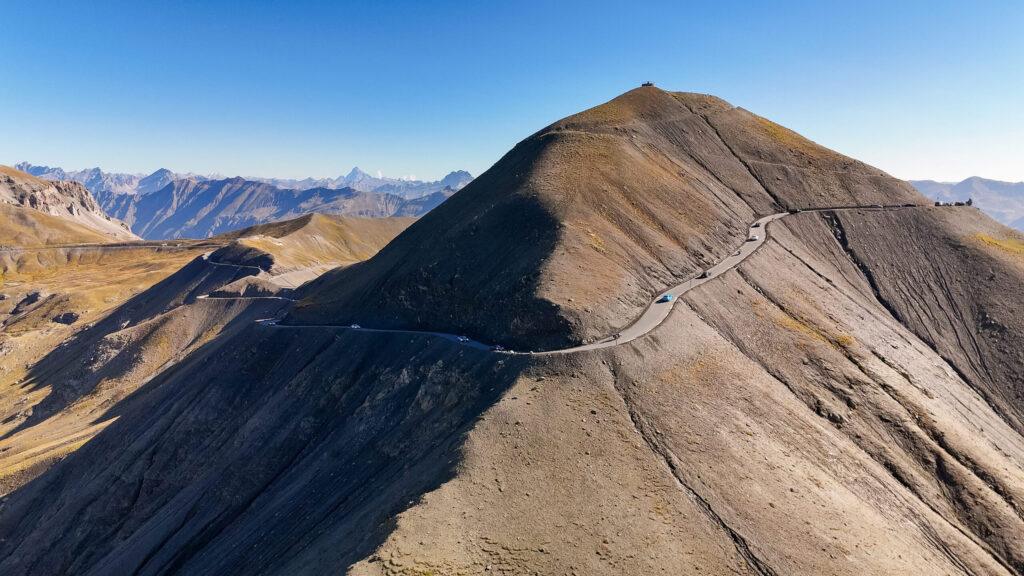 Kurvenreiche Straße auf einem spektakulären Hochgebirgspass in den Alpen, umgeben von beeindruckenden Berglandschaften.