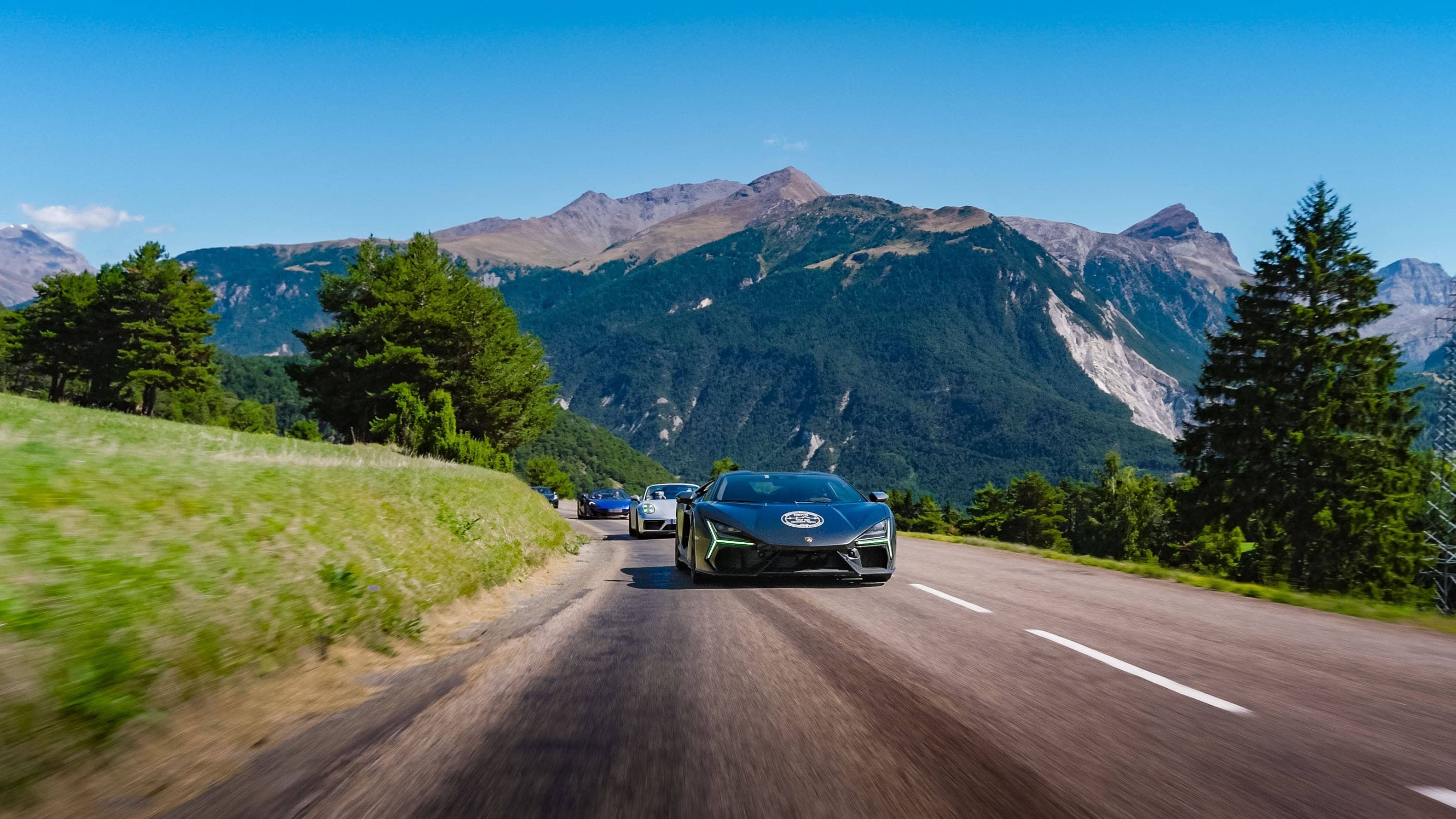 Ein atemberaubendes Abenteuer mit Supersportwagen auf malerischen Alpenstraßen unter strahlend blauem Himmel.