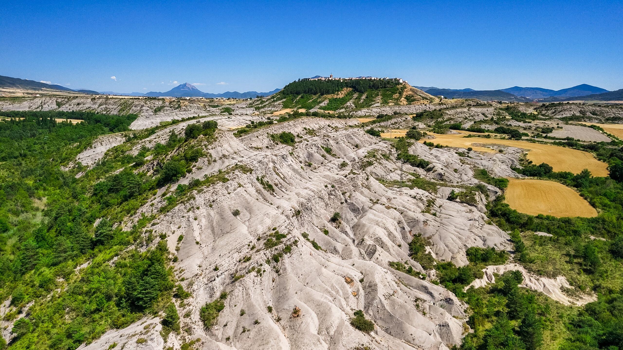 Panoramablick auf malerische Landschaft mit Hügeln und Wald in der Ferne.