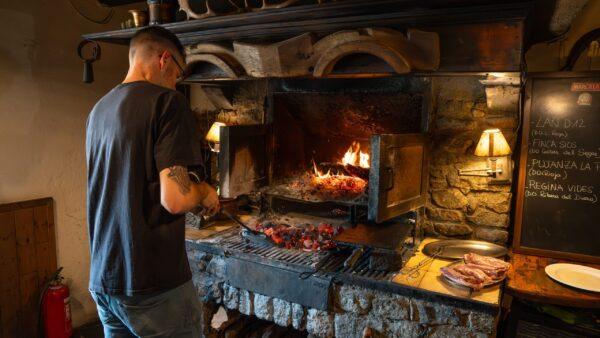 Mann grillt im traditionellen Holzofen in gemütlichem europäischen Restaurant.