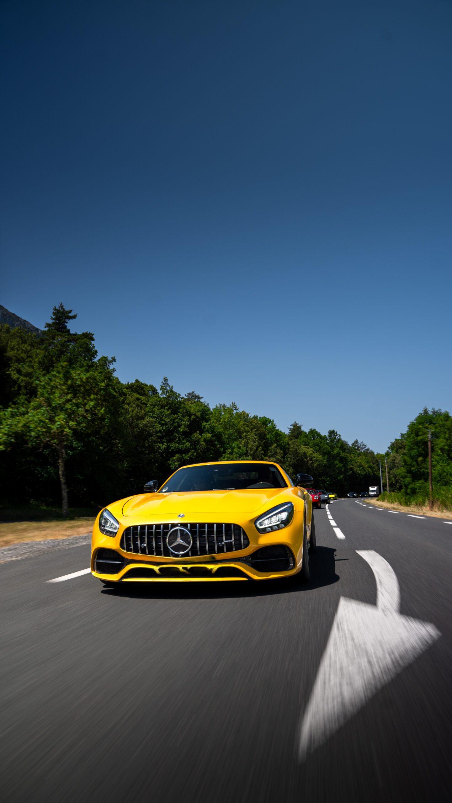 Gelber Mercedes-AMG GT in voller Fahrt auf einer Landstraße während eines exklusiven Driving-Events.